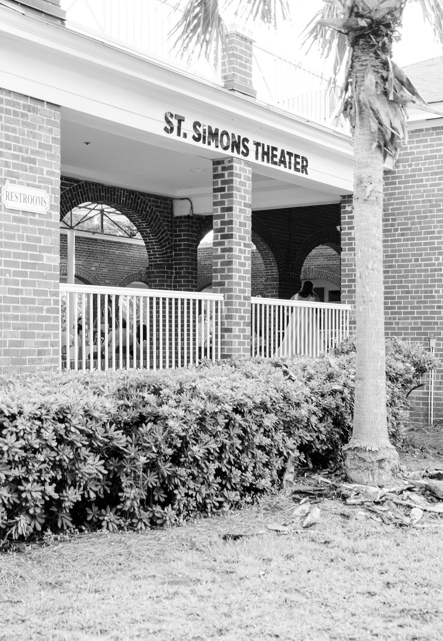 The St. Simons Theater entrance features white columns, brick walls, and lush landscaping along its exterior.