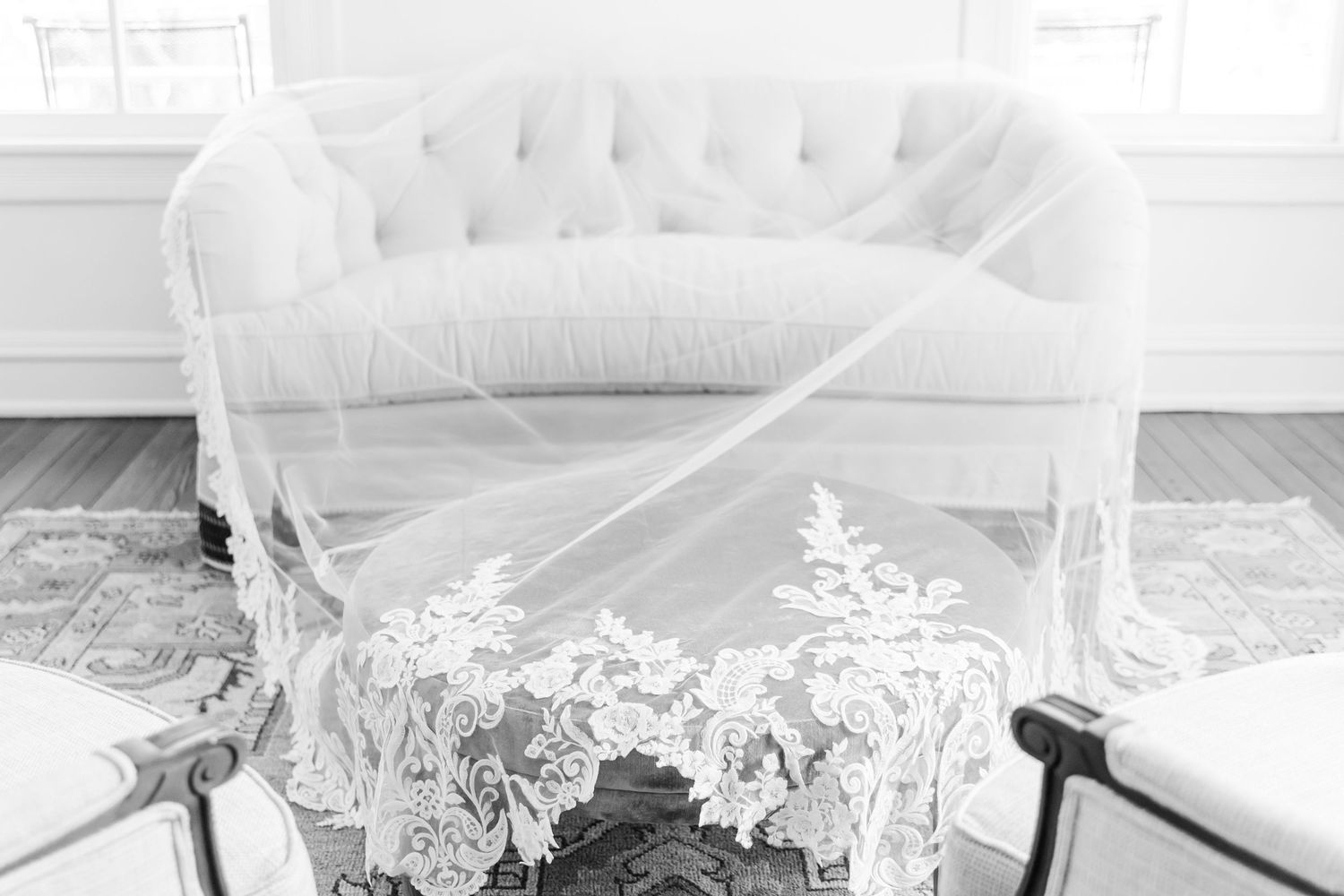 Elegant white lace veil draped over a tufted sofa in a bright bridal suite.