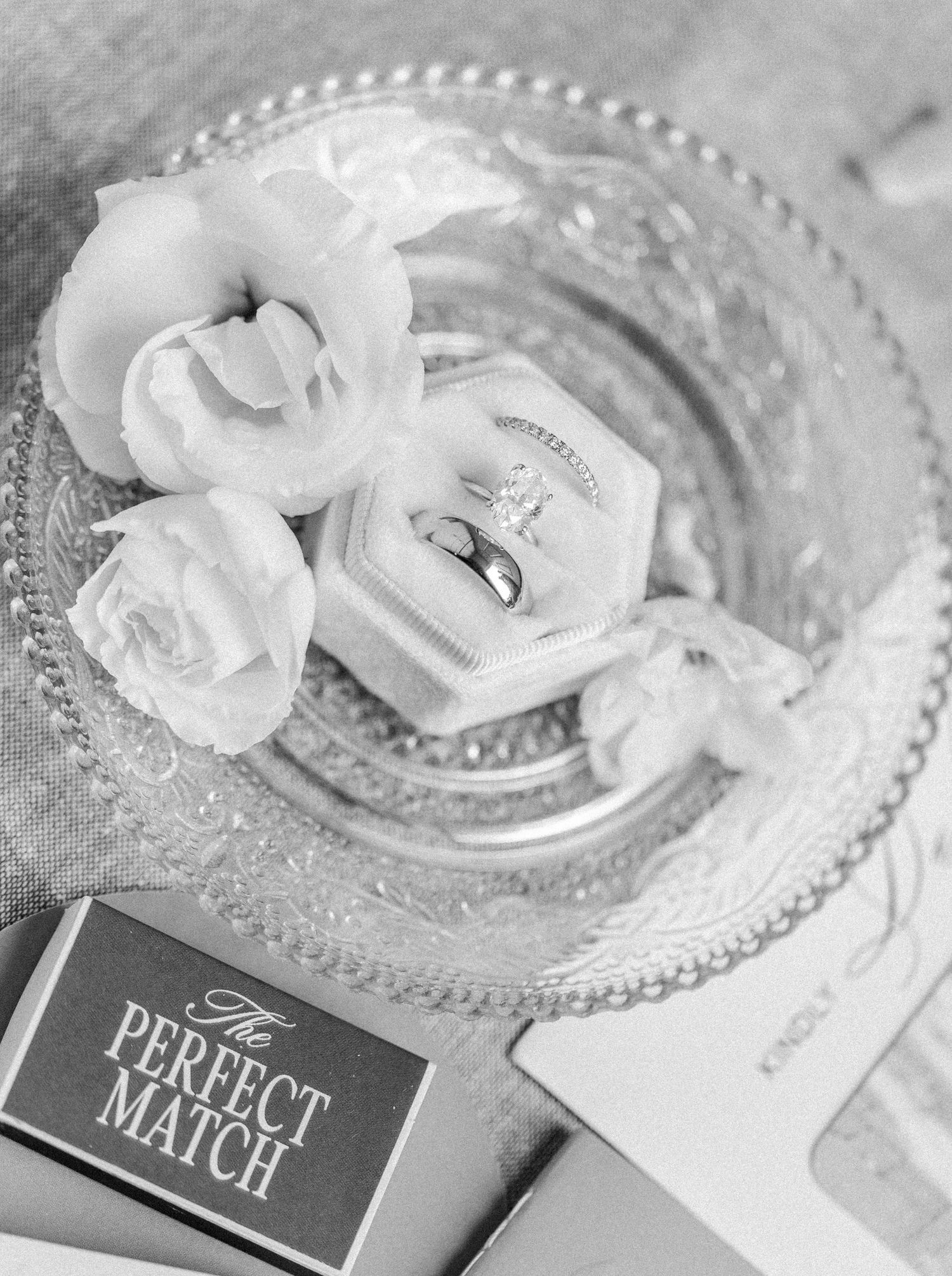Wedding place settings with crystal charger plates and white roses displayed with name cards.
