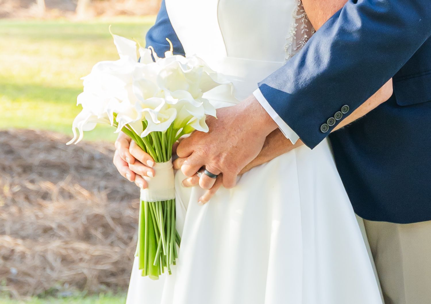 A close-up of hands holding a white floral bouquet with paperwhite narcissus flowers against a blurred background.