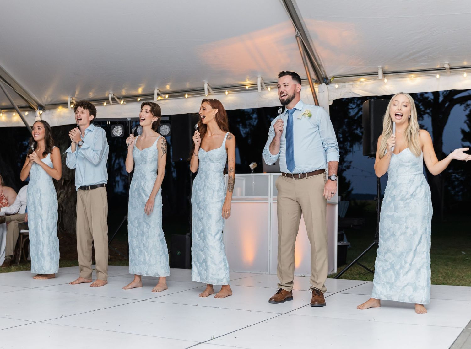 Wedding party members dance together in a line on the dance floor during an evening reception celebration.