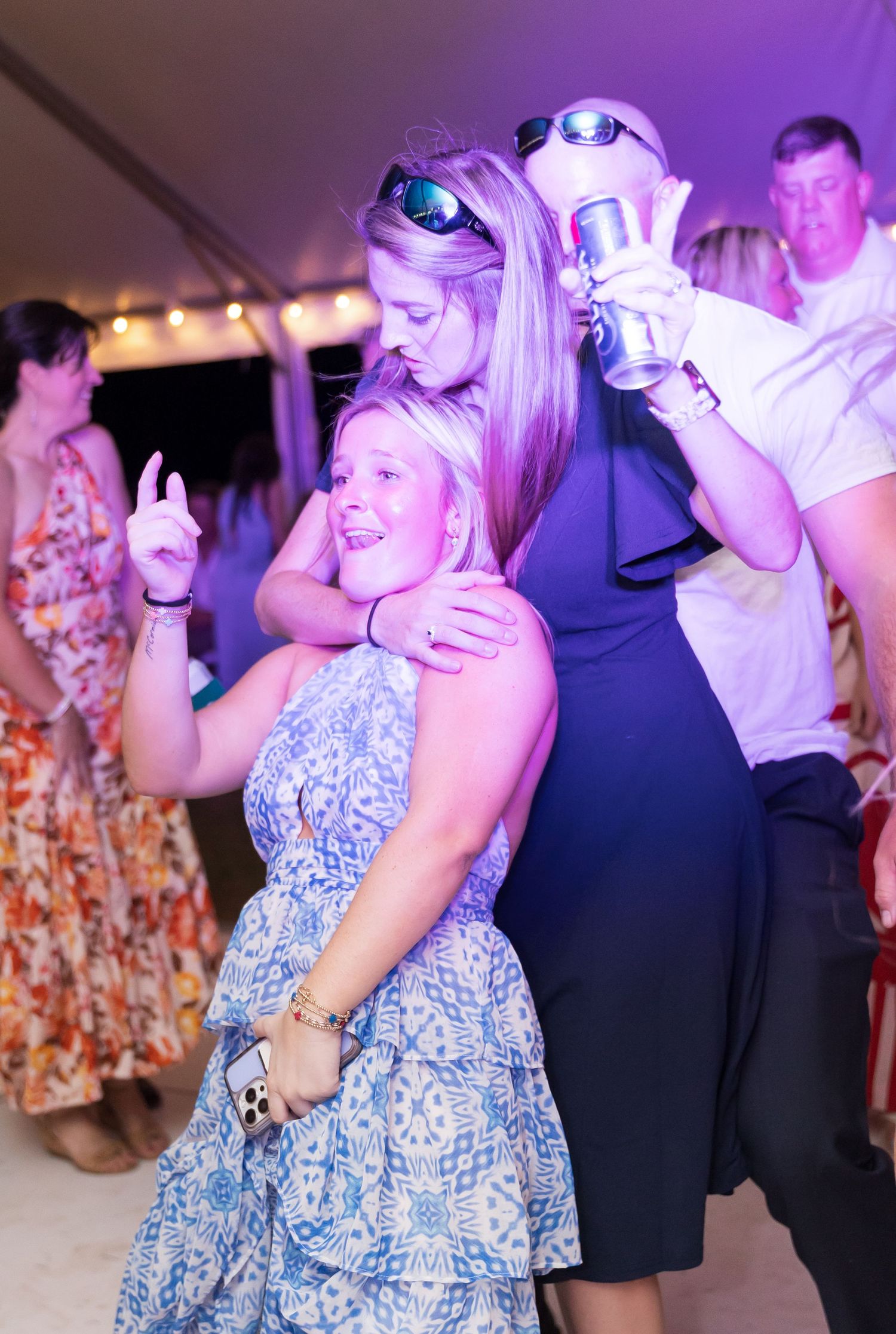 People dancing under purple lighting at a wedding reception party.