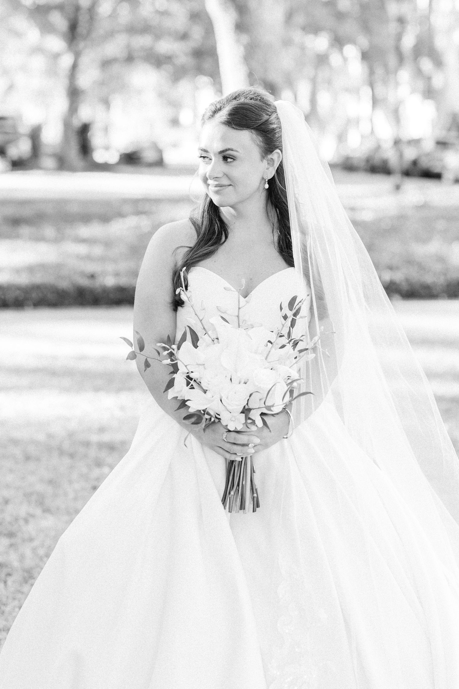 Ethereal bridal portraits in white gown holding classic white bouquet outdoors.