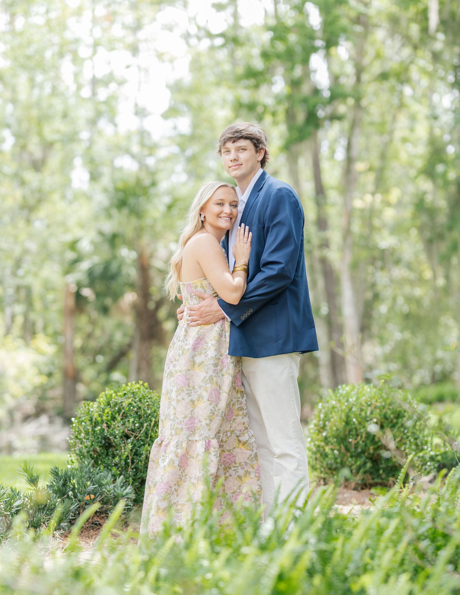 A romantic embrace in a Southern garden with Spanish moss and manicured shrubs.
