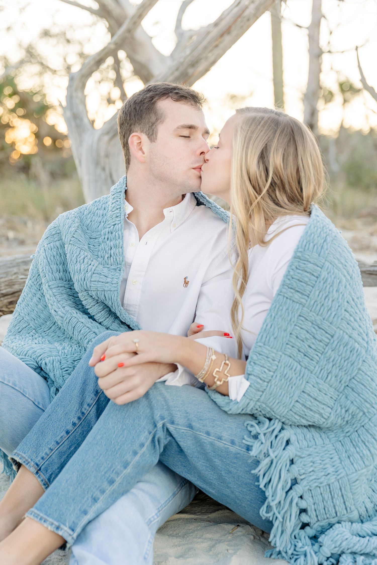 Couple in casual attire sharing a romantic moment outdoors with a blue sweater draped around them.