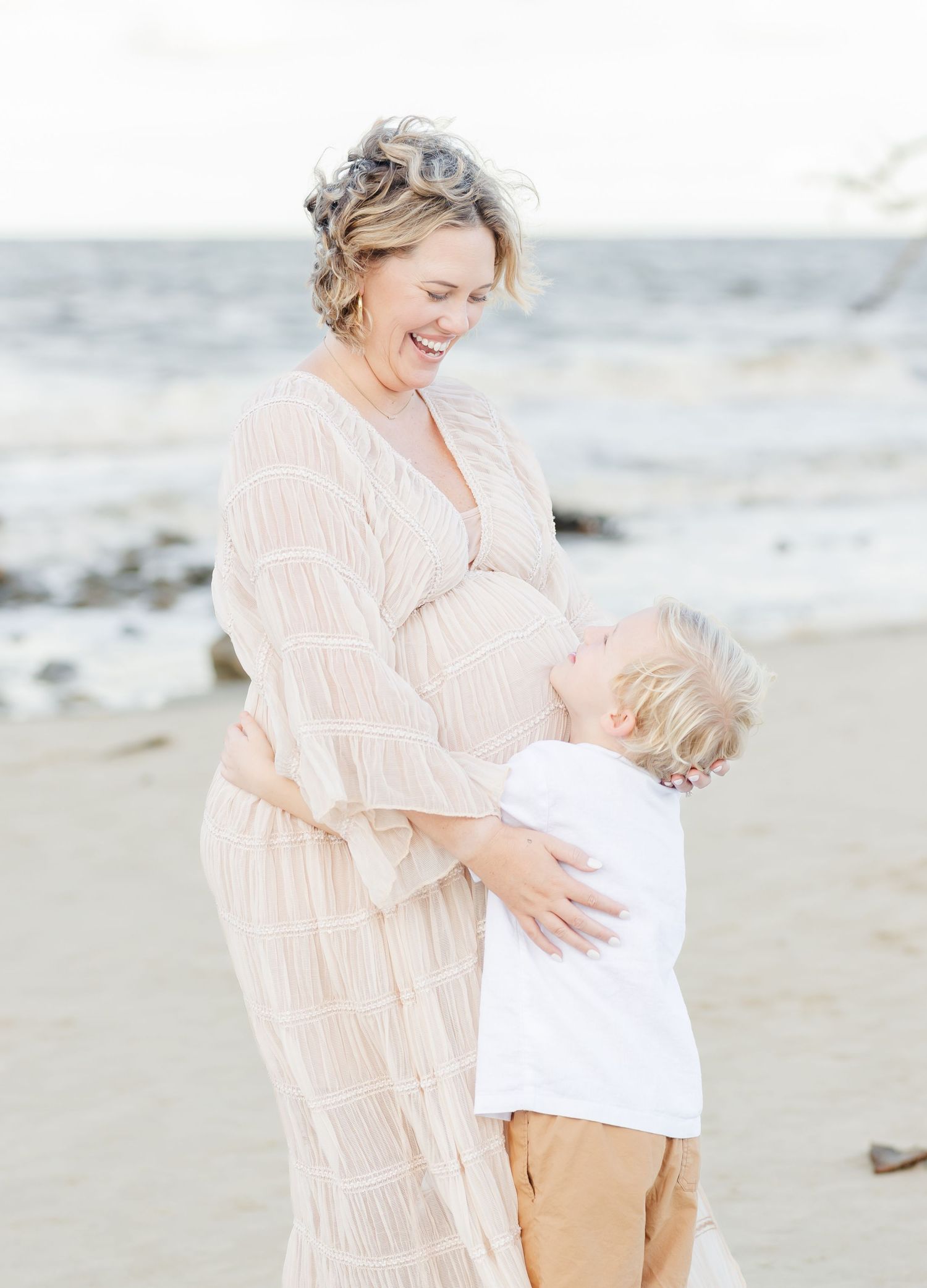 Family bonding moment captured on a sunny beach with soft neutral colors.