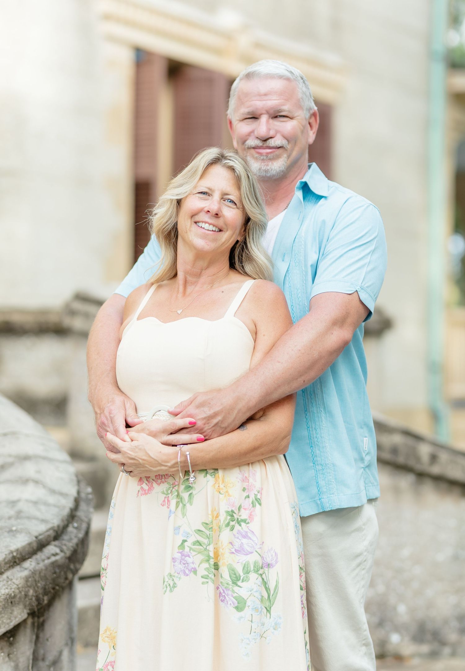 A happy senior couple embraces and laughs together in a romantic outdoor photoshoot.