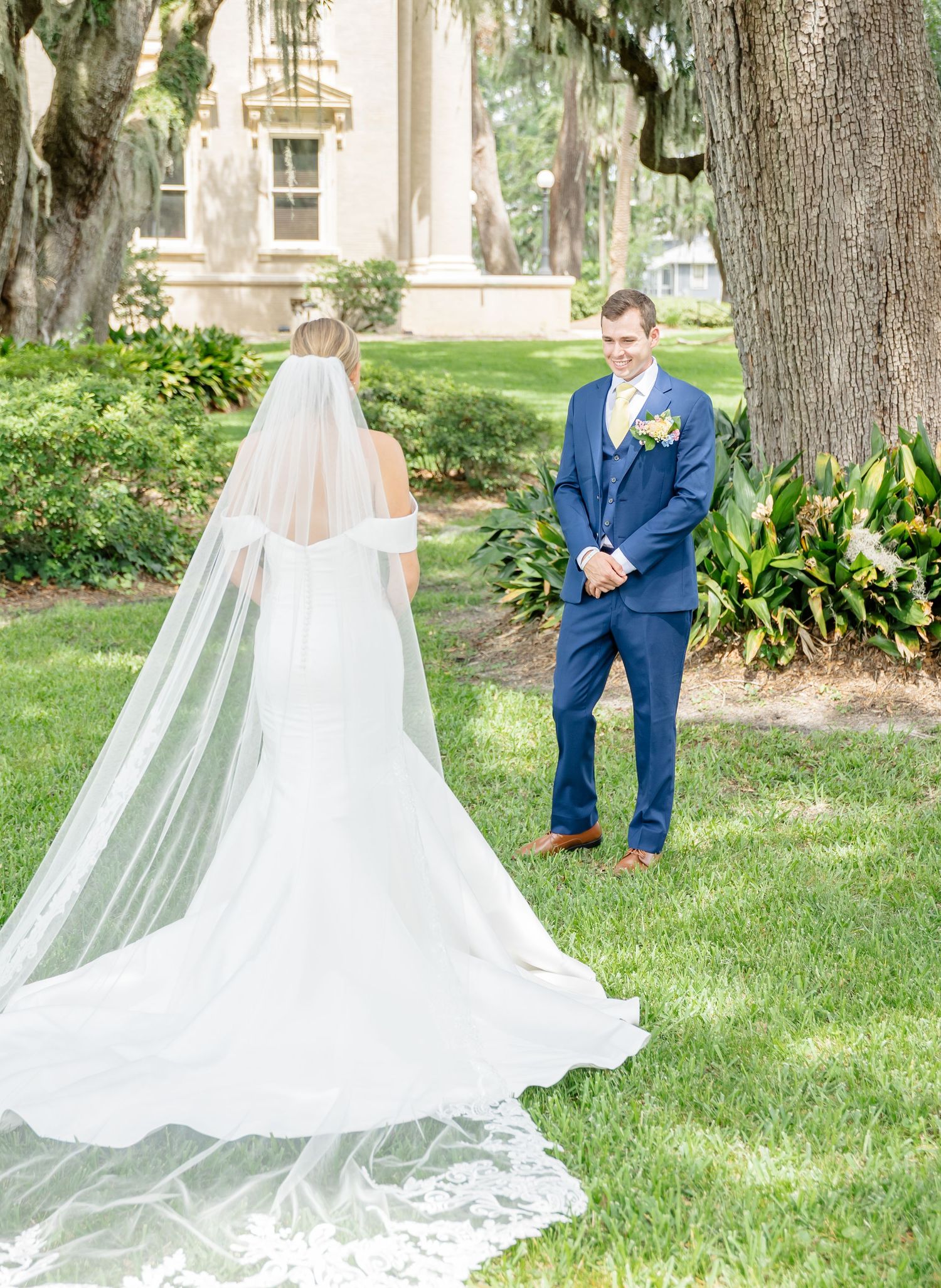 Wedding ceremony setting under Spanish moss trees with long flowing veil and elegant architecture.