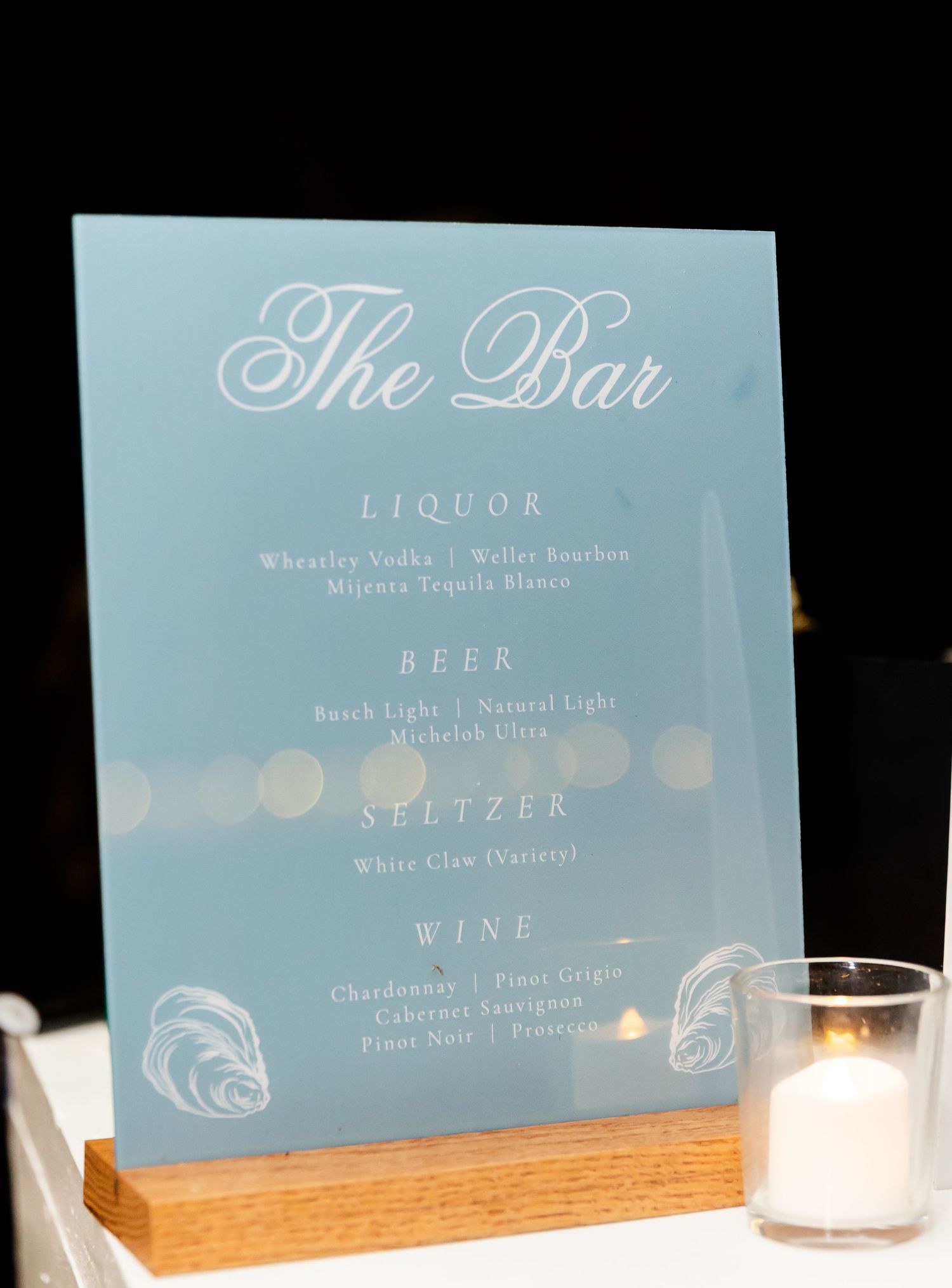 Light blue wedding bar menu signs displayed on wooden stands featuring drink selections.