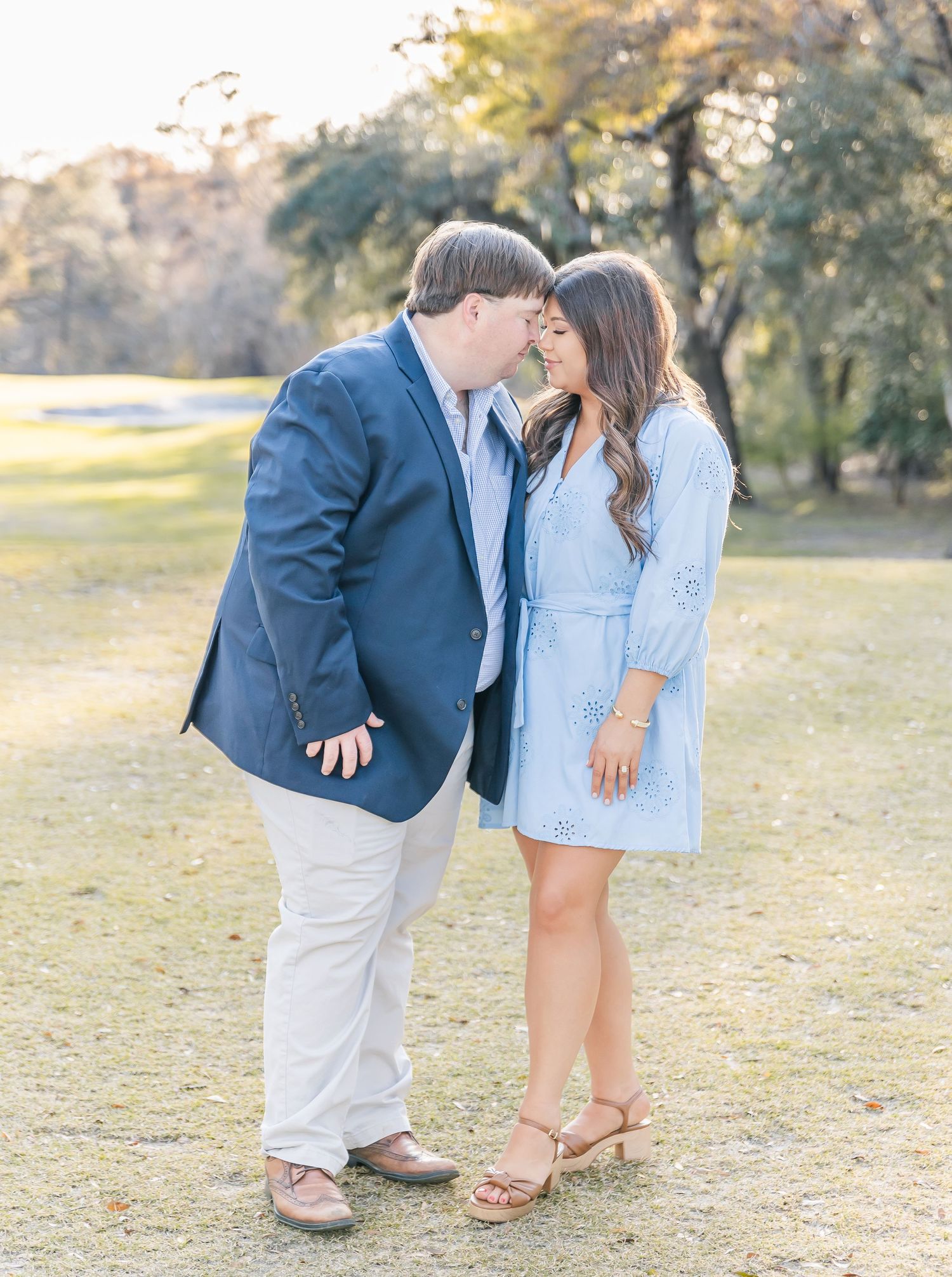 A loving couple shares a tender moment on a sunlit garden path wearing coordinated spring outfits.