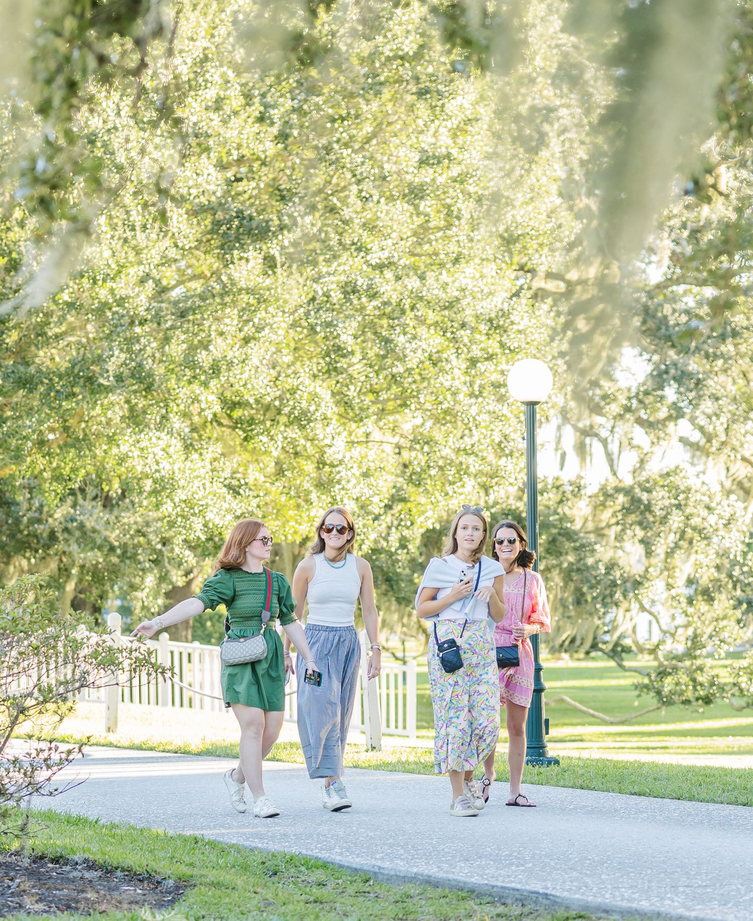 Group of people walking together on a winding gravel path through a sunny park on a bright summer day.