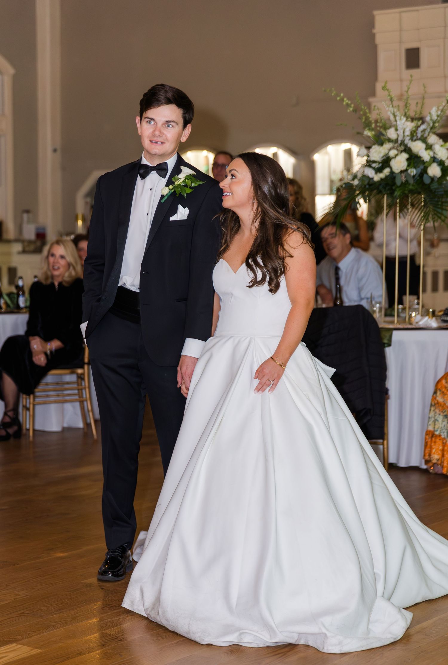 Bride in white ballgown and groom in black tuxedo share a moment during their wedding reception.