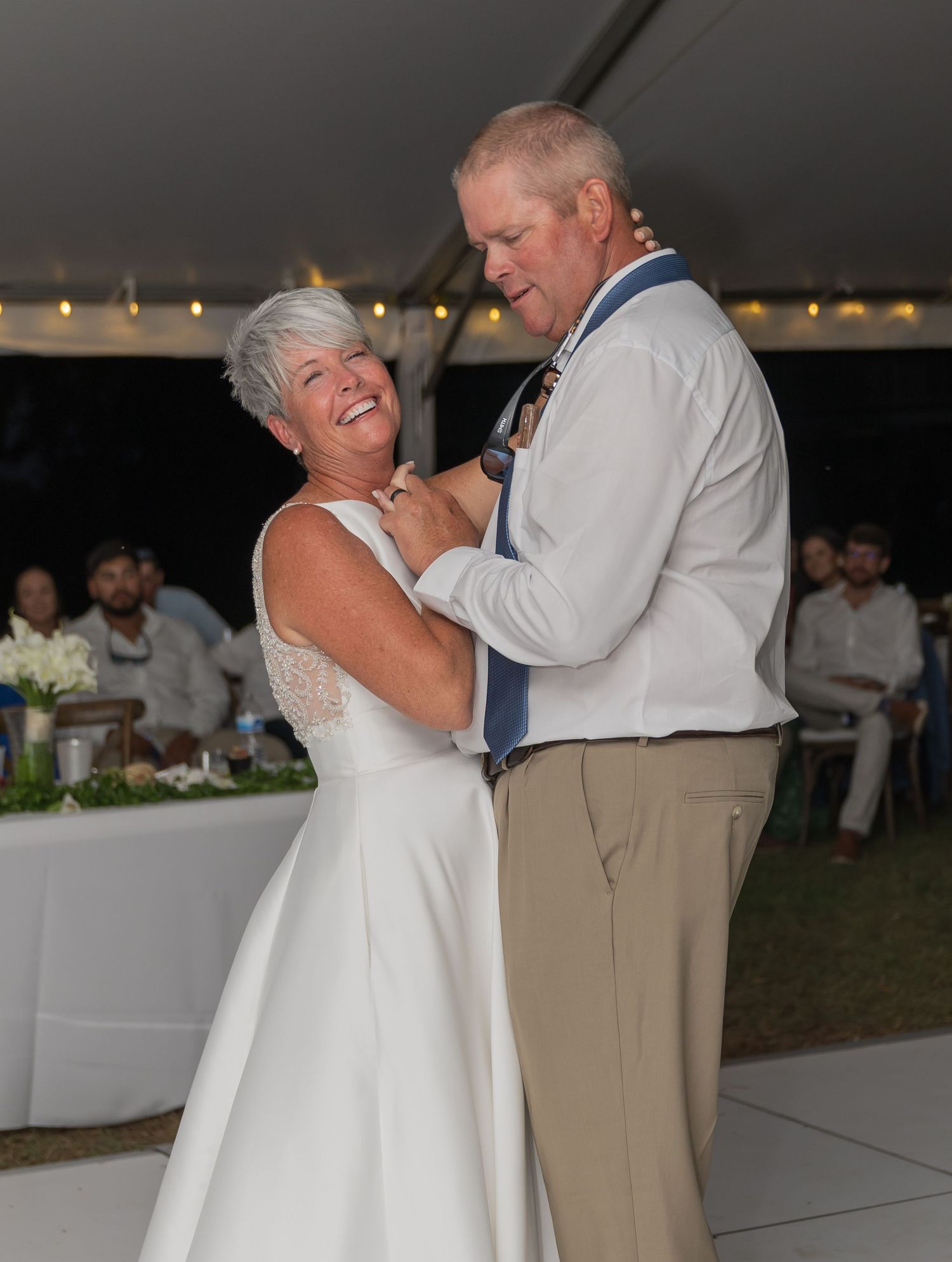 Couple sharing a romantic dance moment at an outdoor wedding reception.