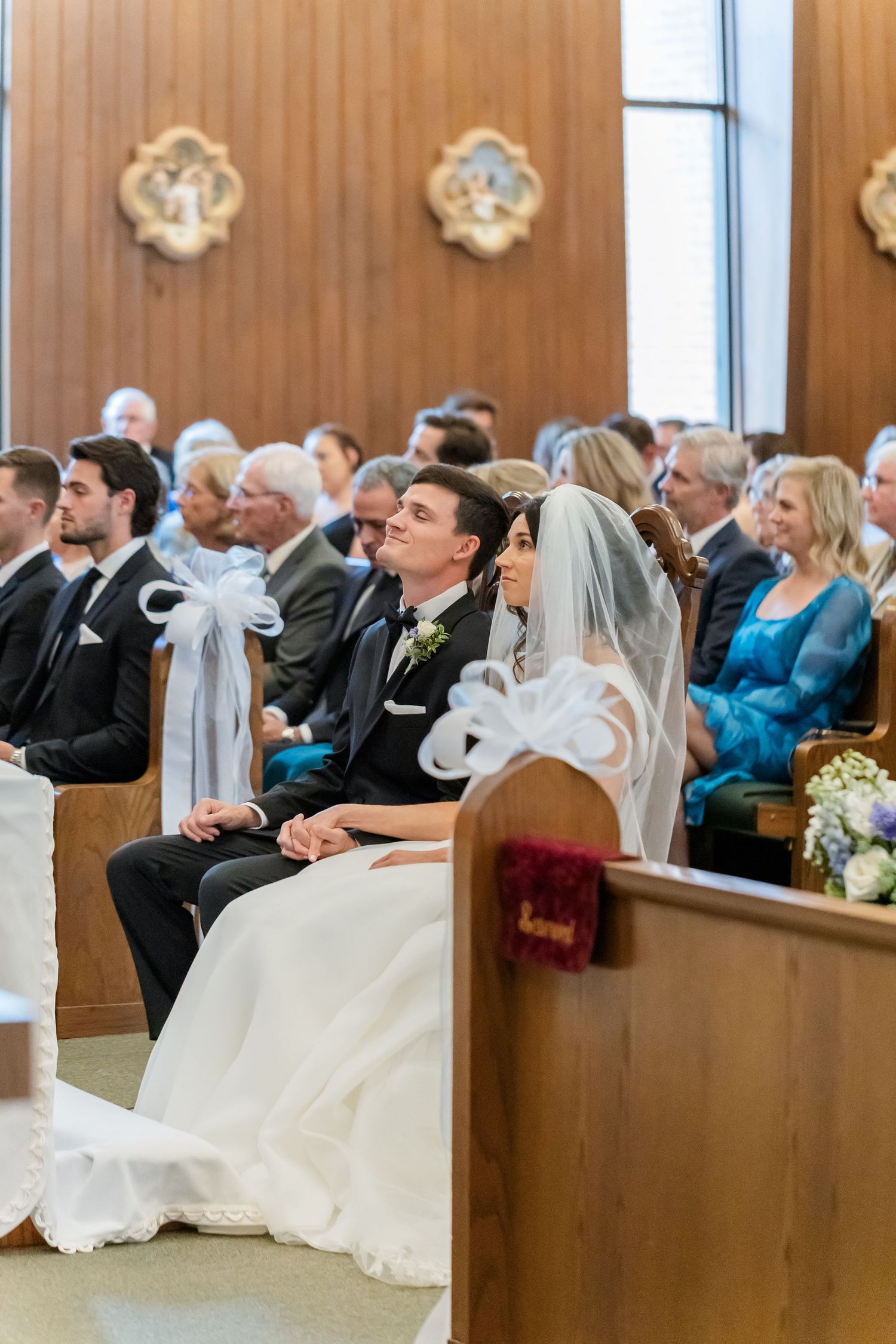 Wedding guests and bridal party seated in church pews during ceremony.