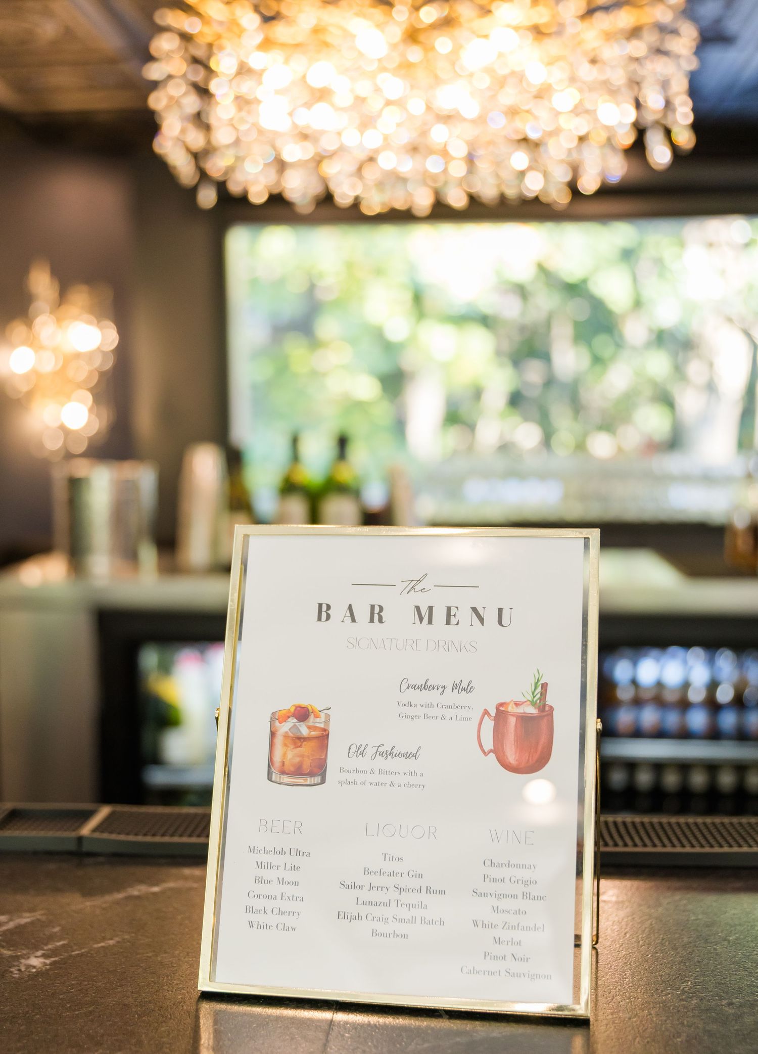 Elegant bar menu displays with cocktail illustrations under warm lighting at a wedding reception.
