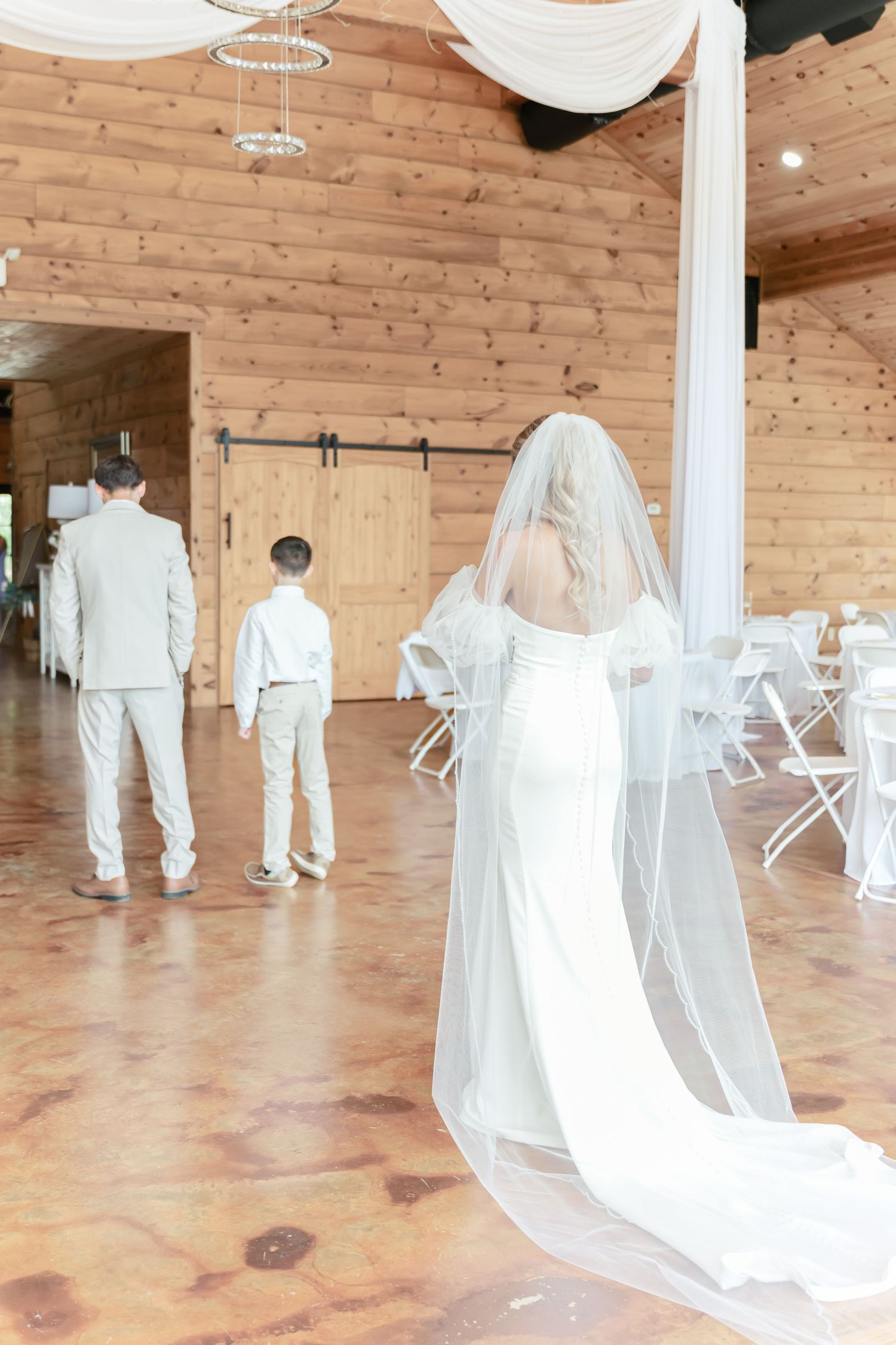 A wedding ceremony scene in a rustic barn venue with wooden walls and floors.