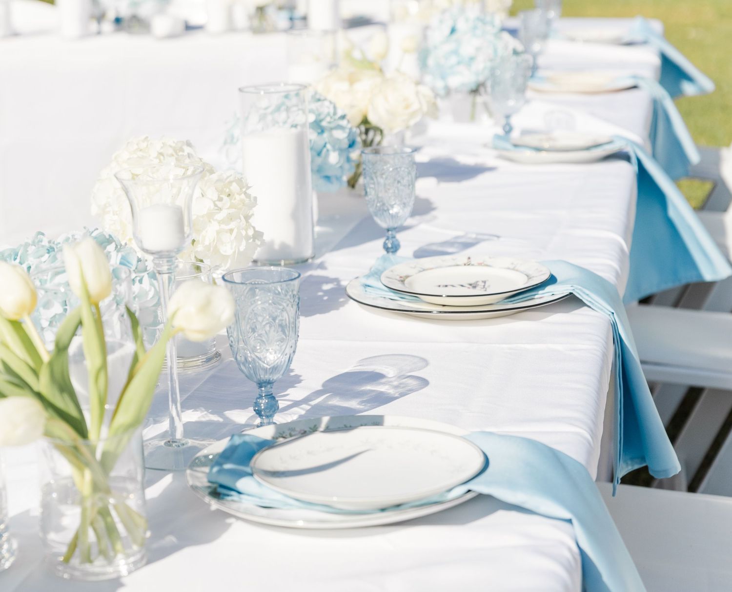 Elegant outdoor wedding reception table with blue ribbons and hydrangeas.