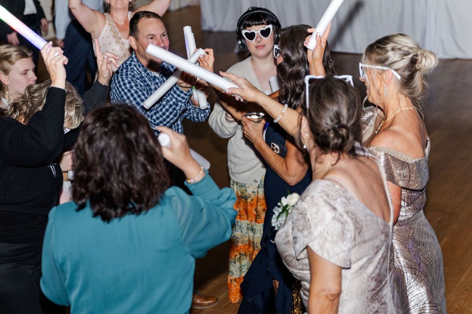 Wedding guests dancing and celebrating with glow sticks at a lively wedding reception party.