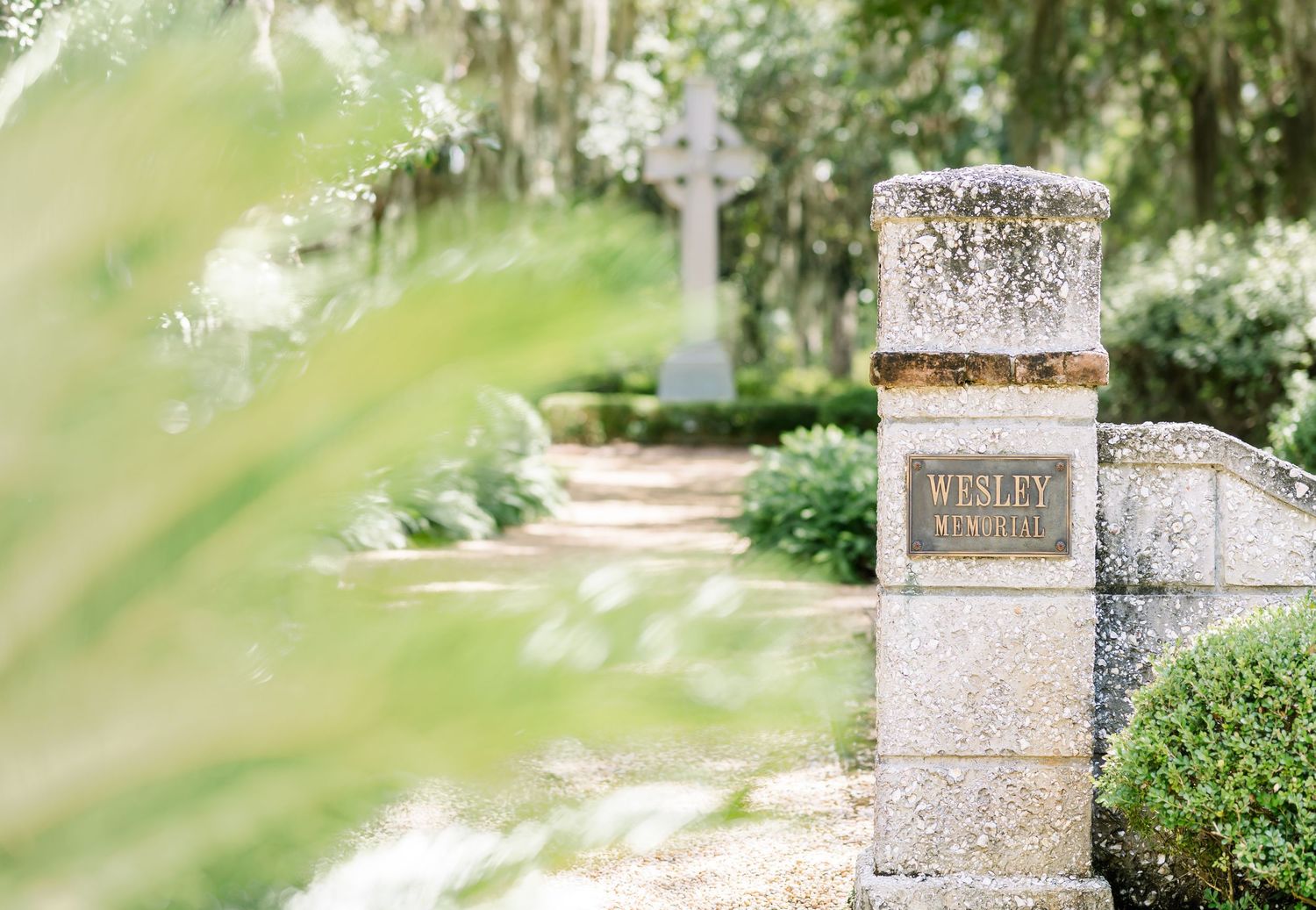 A decorative stone pillar stands among green foliage in a tranquil garden setting.