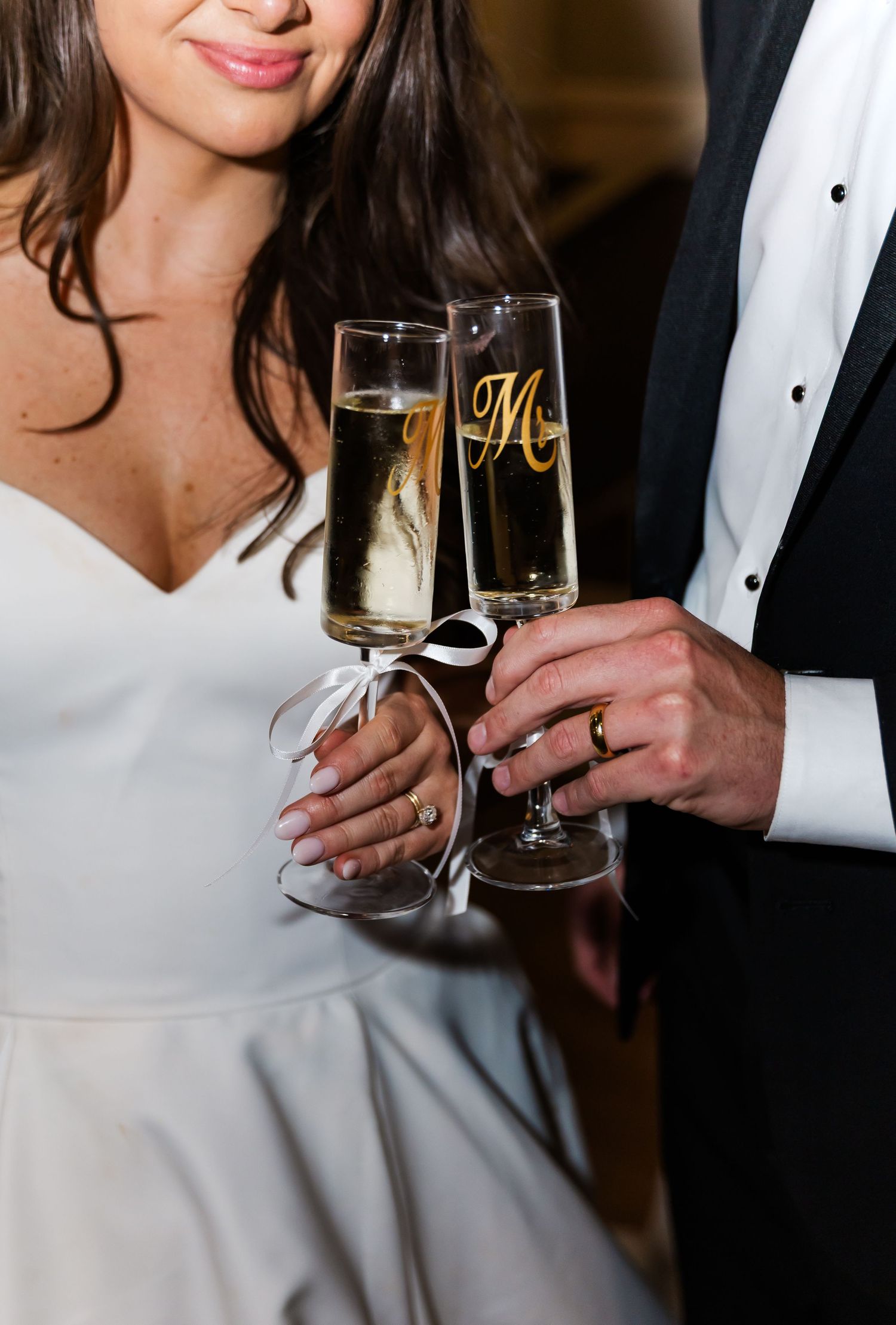 A couple in formal attire clinks champagne glasses while celebrating at an elegant event.