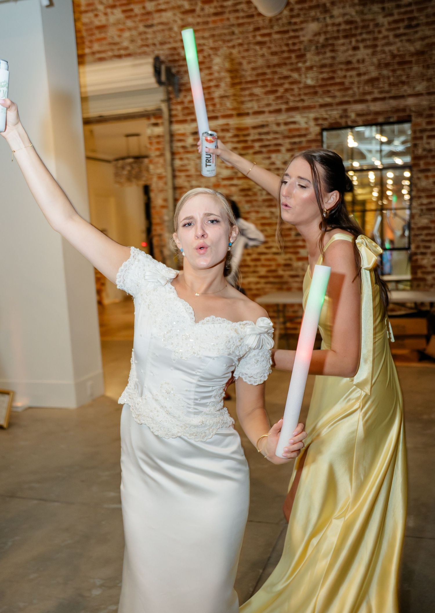 Wedding celebration with guests in yellow dresses and white gowns dancing with glow sticks.