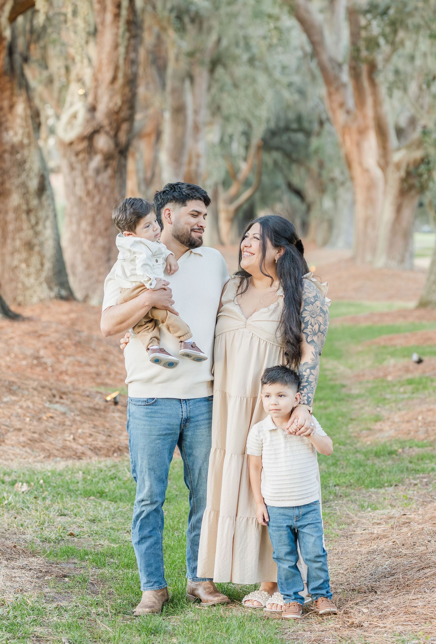 A family shares a joyful moment together on a path lined with tall eucalyptus trees.