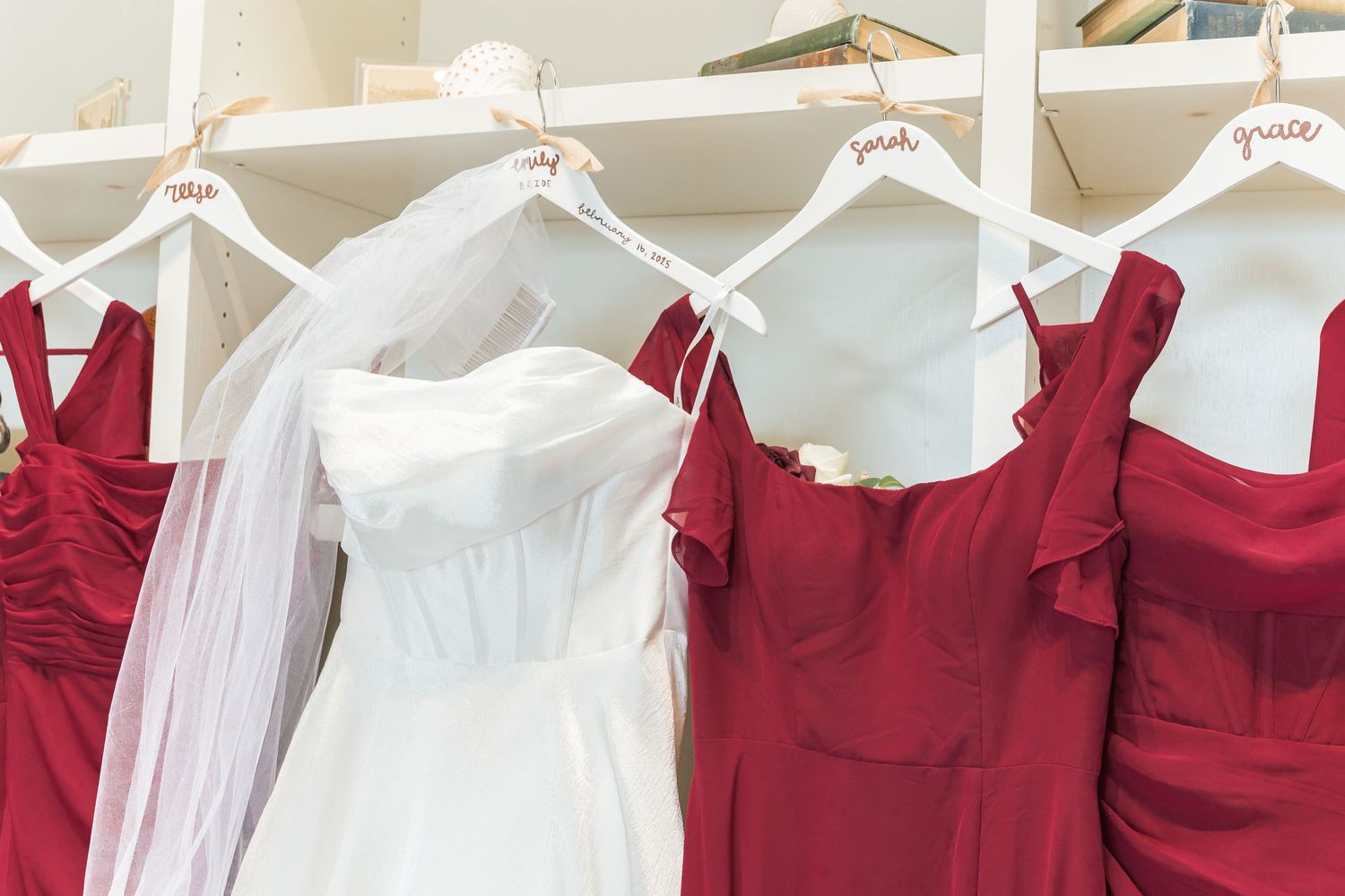 Bridesmaid dresses in red and white hanging on display with wedding veil.