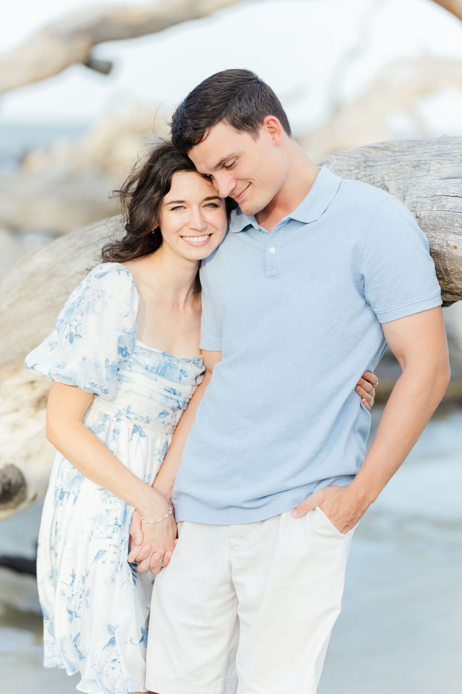 A romantic coastal photoshoot featuring a couple in matching light blue and white attire.