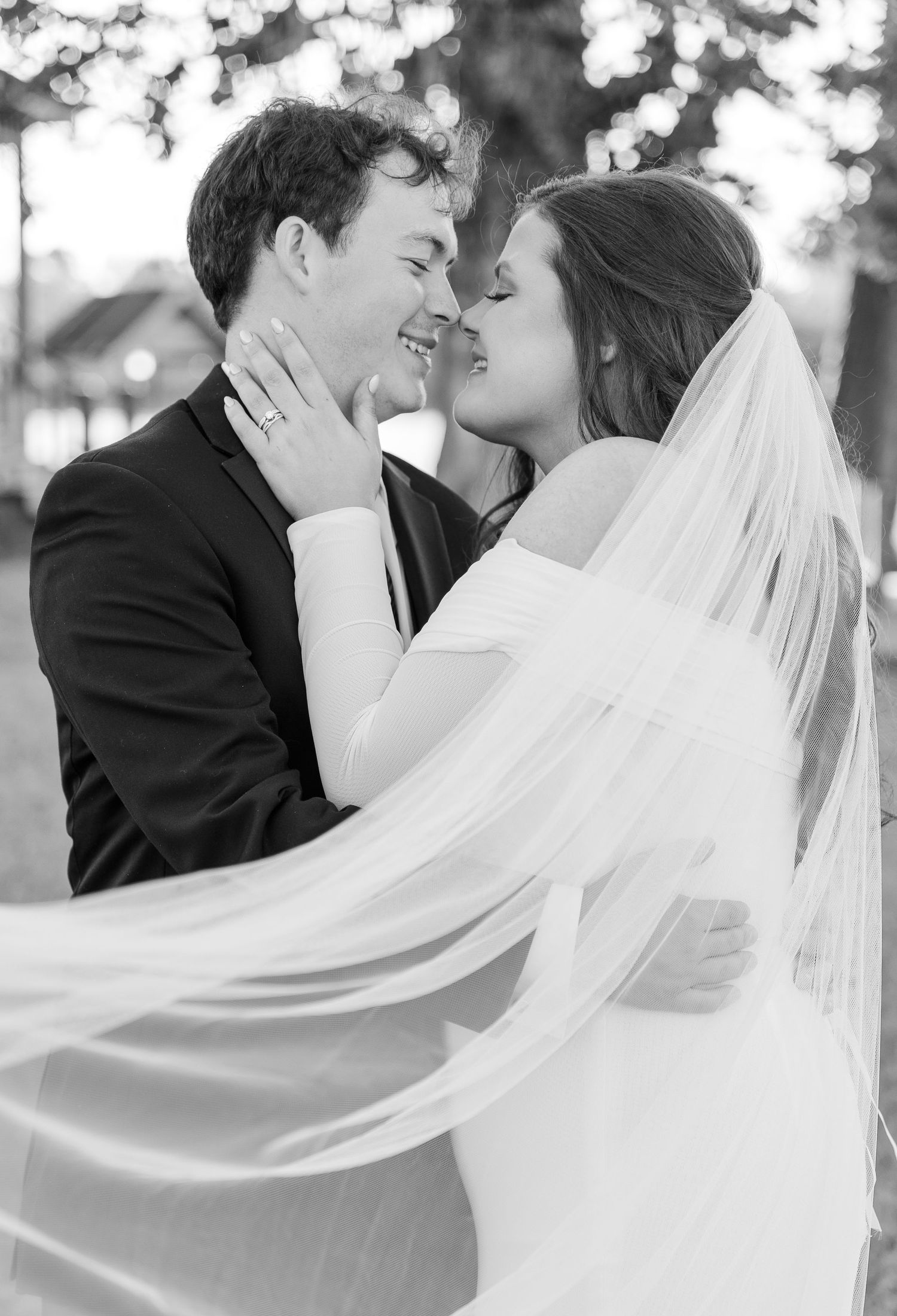Black and white wedding portrait with flowing veil capturing romantic moment.