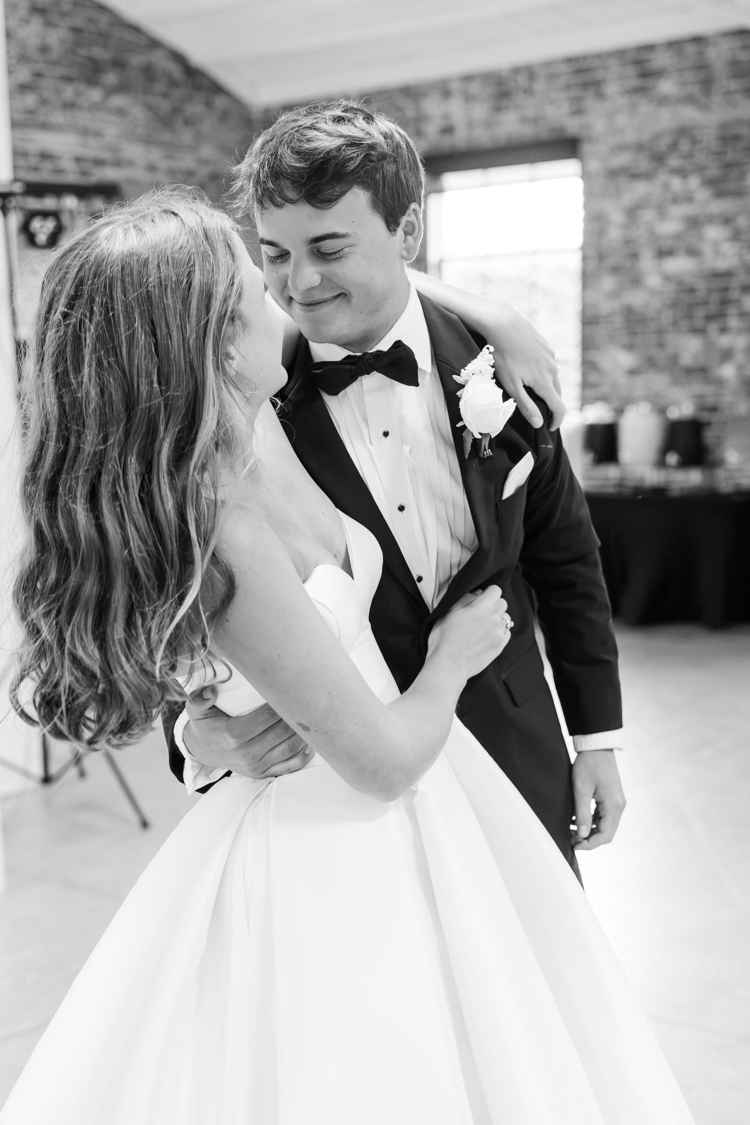 Black and white photo of bride and groom sharing intimate first dance at wedding reception.
