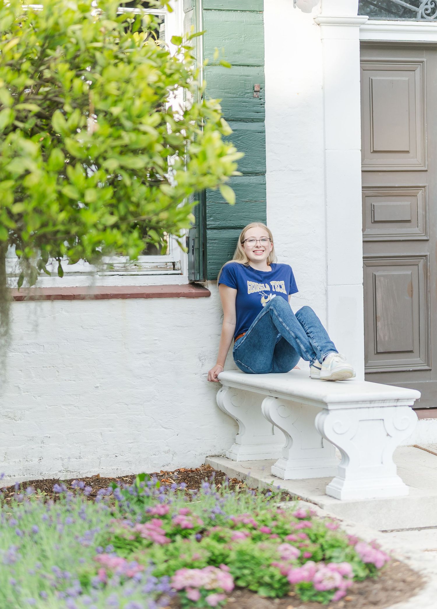 Person in casual attire sits on white stone bench surrounded by garden landscaping.