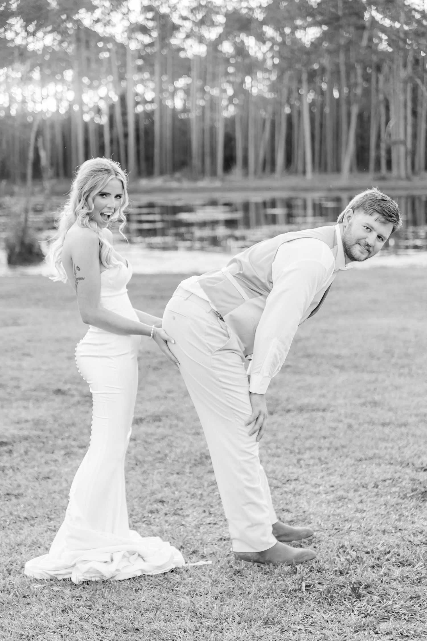 Fun black and white wedding photo showing couple striking humorous pose outdoors.