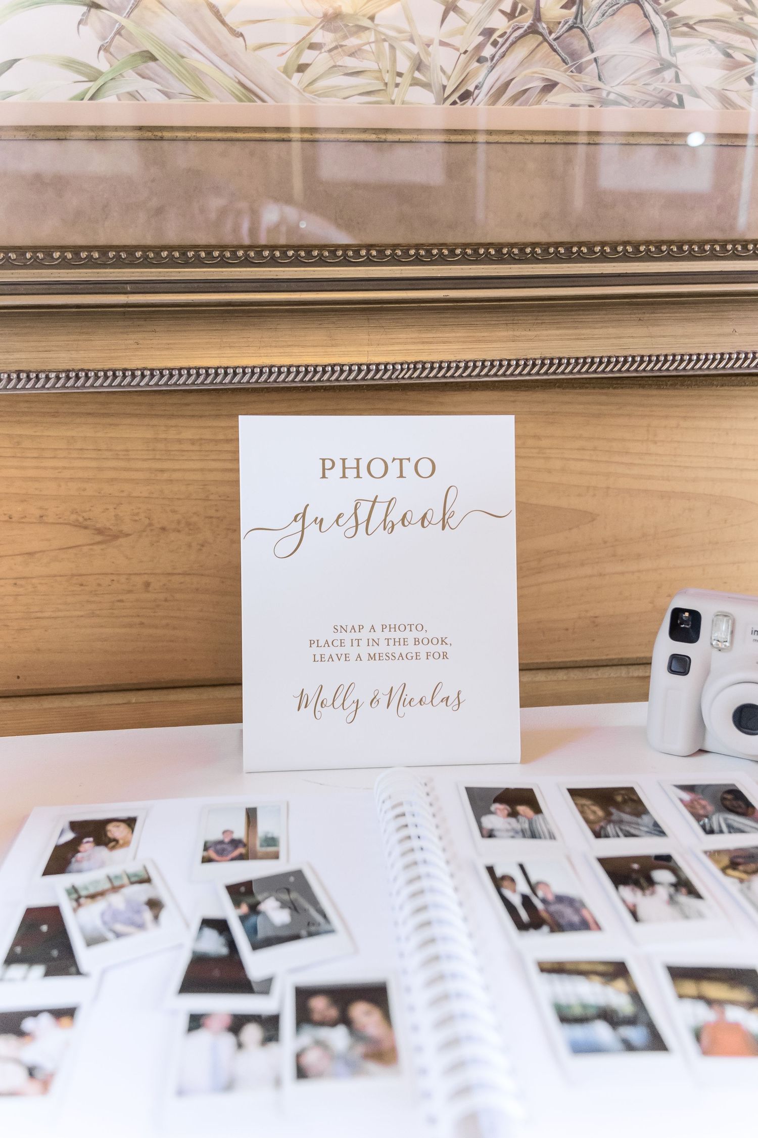 Photo guestbook display with instant photos and wedding album on wooden surface.