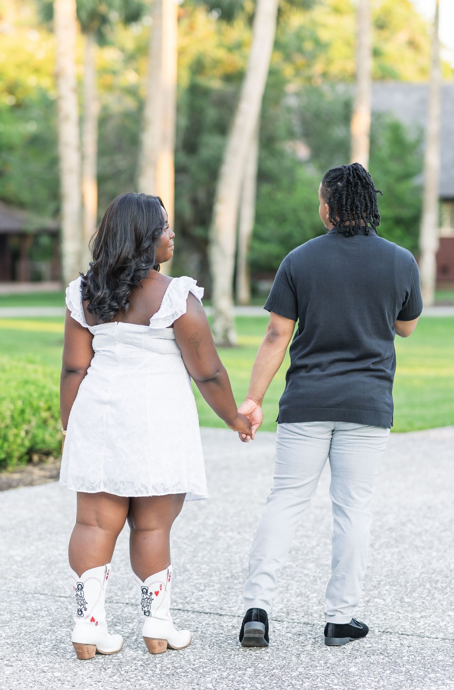 A couple walking together on a gravel path surrounded by greenery and trees.