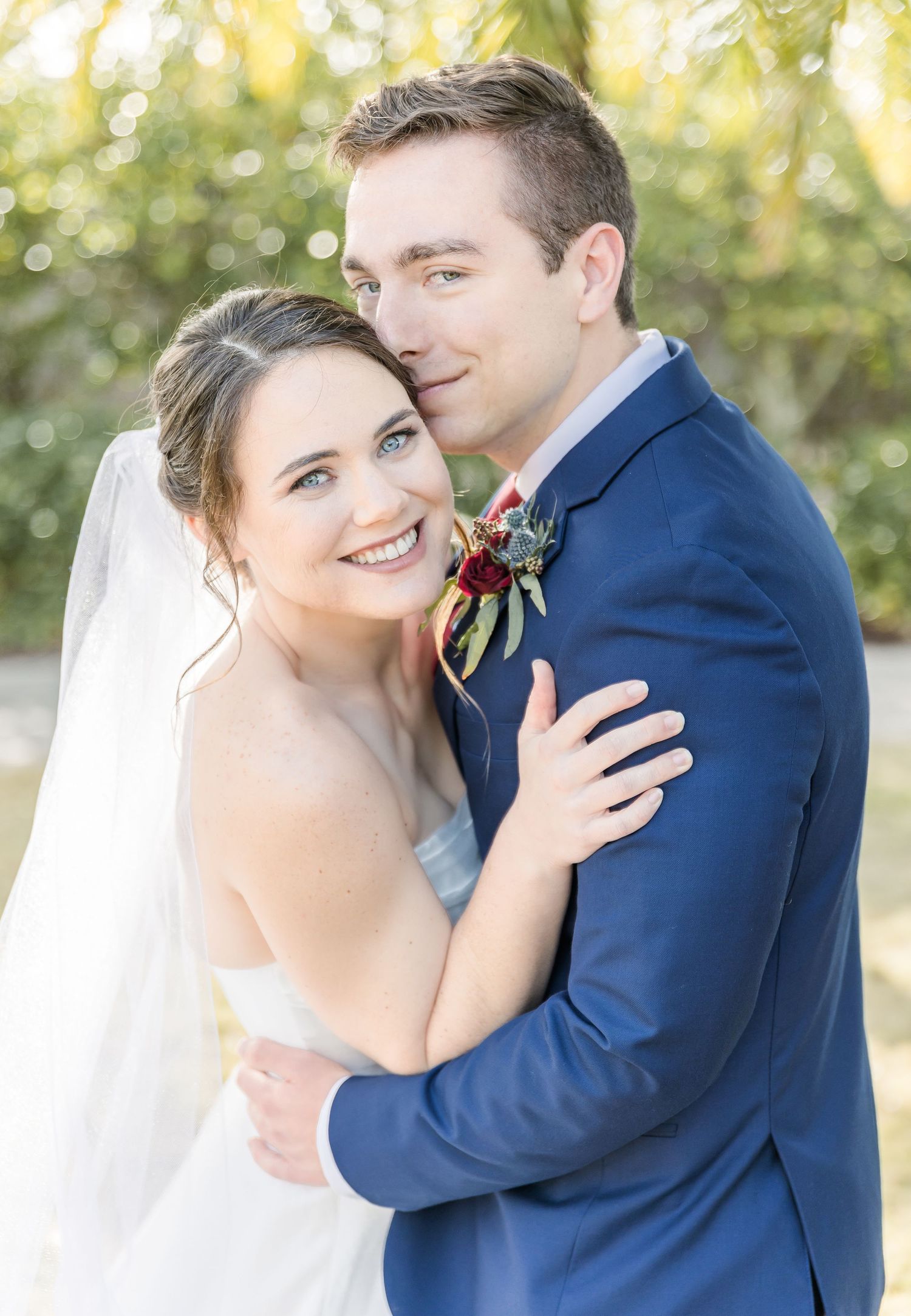 A romantic outdoor wedding portrait with soft natural lighting and palm trees.