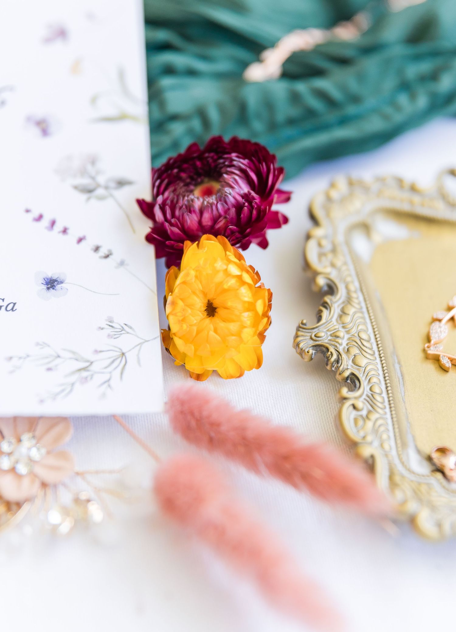 A burgundy and yellow flower arrangement with a vintage gold frame and delicate floral sketch on white.