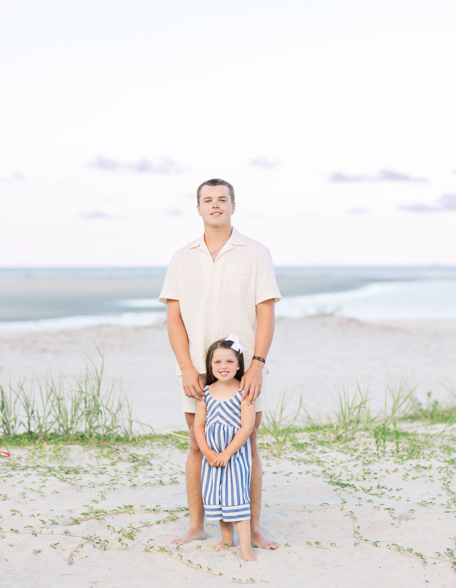 A playful scene at the beach with dune grass and soft pastels during a family photoshoot at sunset.