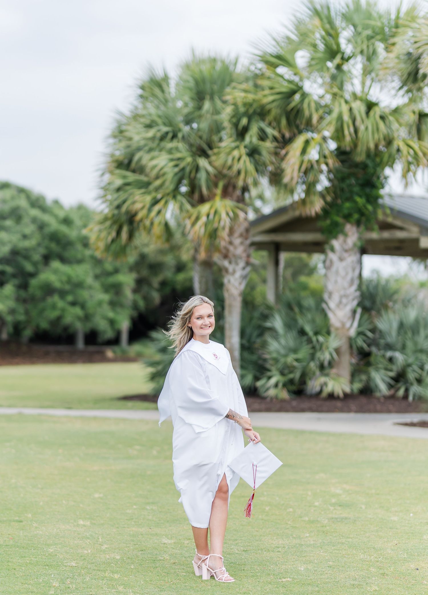 A figure in white twirls on a lawn surrounded by tropical palm trees and a gazebo.