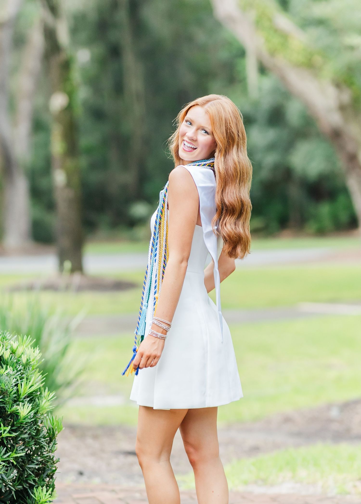 Four sequential photos of someone in a white summer dress posing playfully in a lush garden setting.