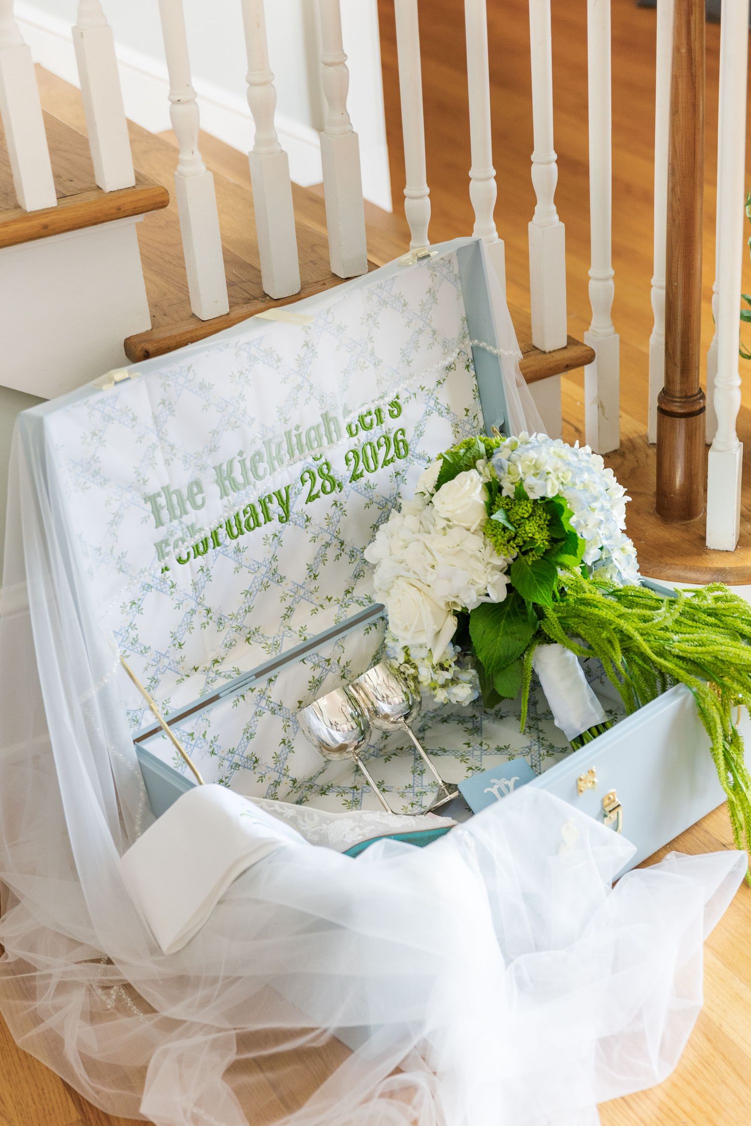 Blue floral wedding memory box with white hydrangea bouquet inscribed The Kicklighters February 28 2026 near staircase.