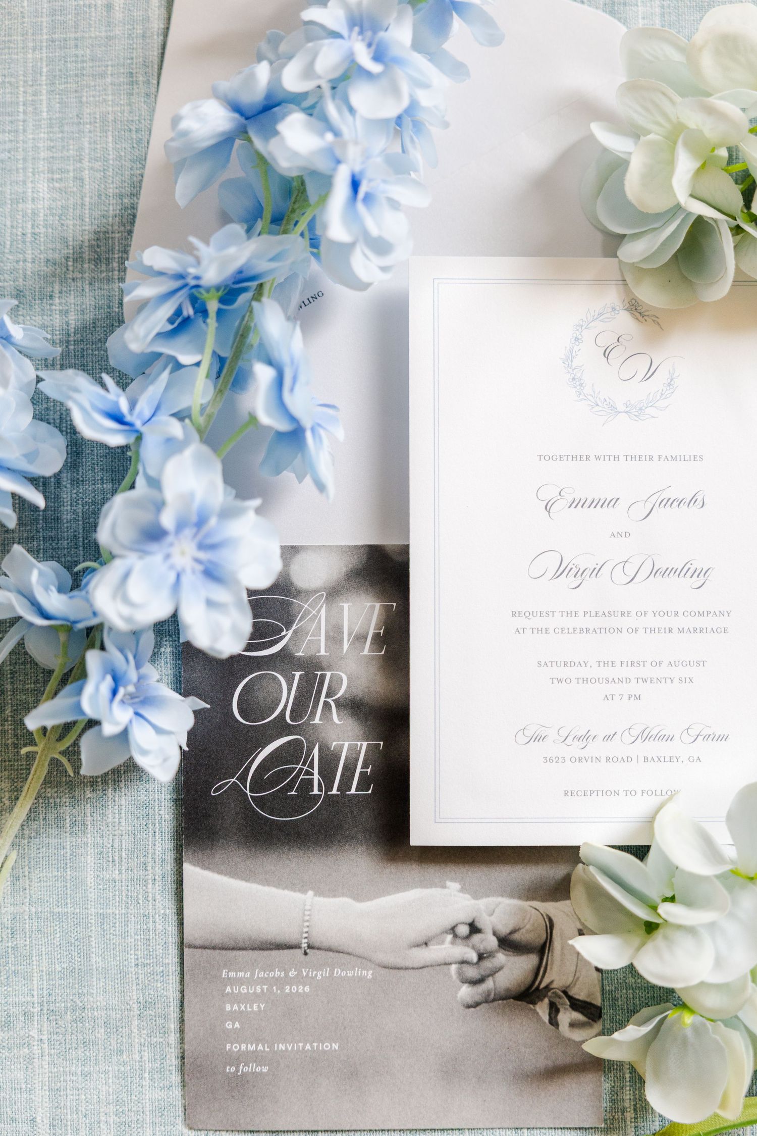 Elegant wedding invitation suite with blue delphinium flowers on a light blue linen background.