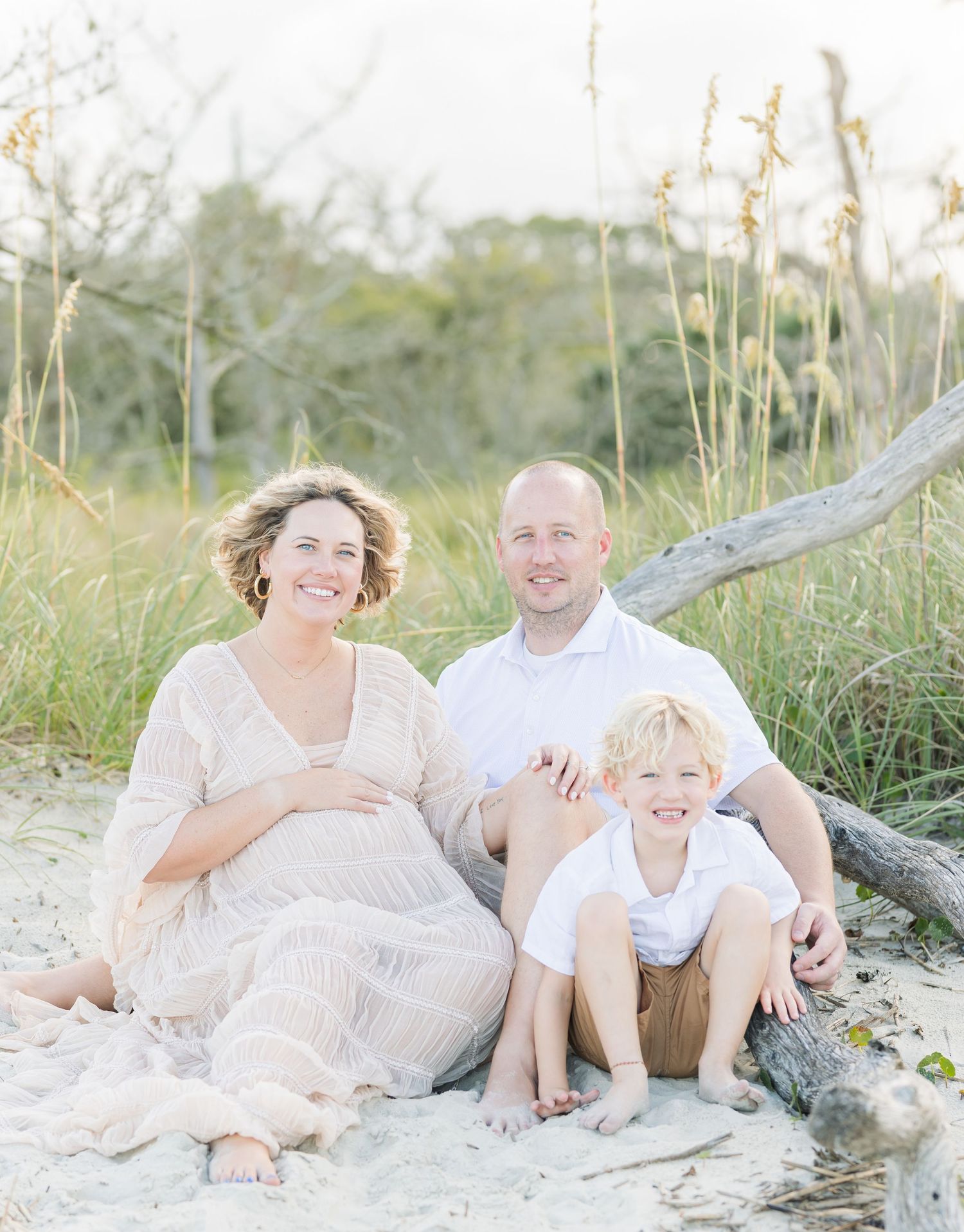 Family beach portraits with neutral colors and natural driftwood setting.