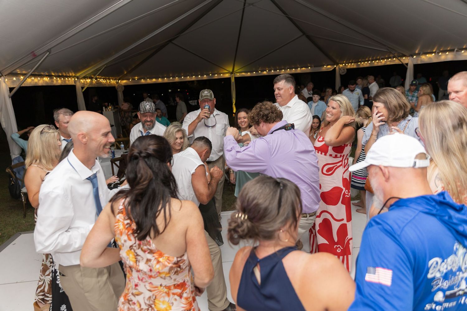 A large group of people dancing and socializing at what appears to be a wedding reception or party event.