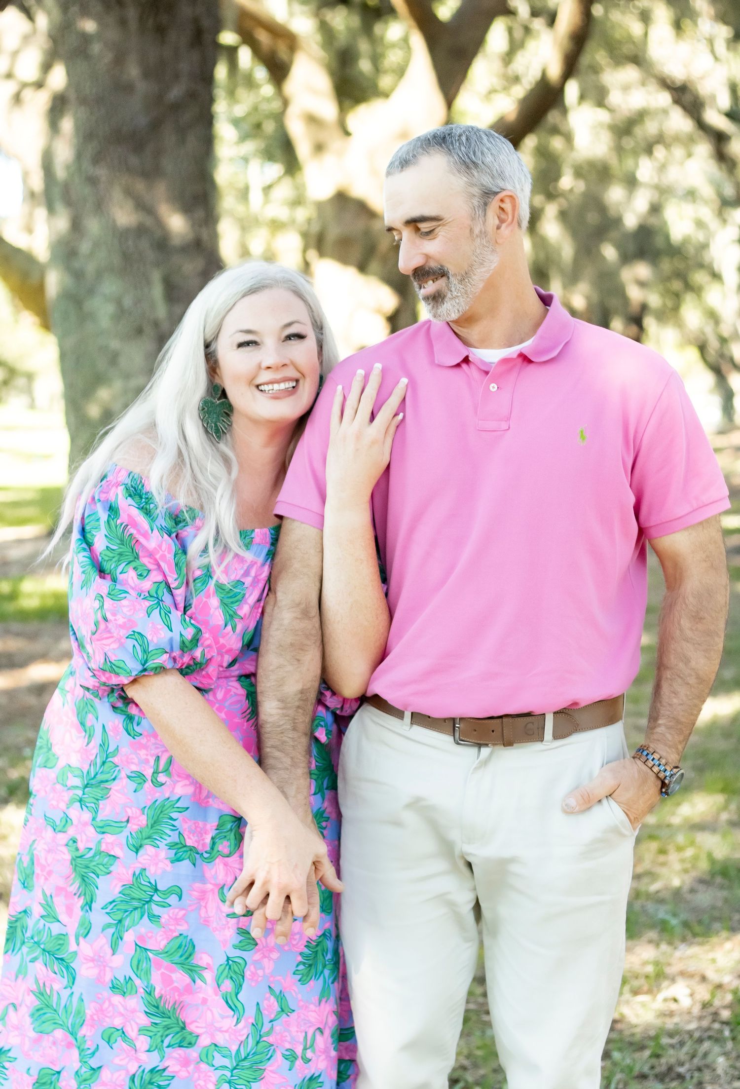 Happy couple sharing a candid laughing moment in vibrant pink and floral summer outfits.