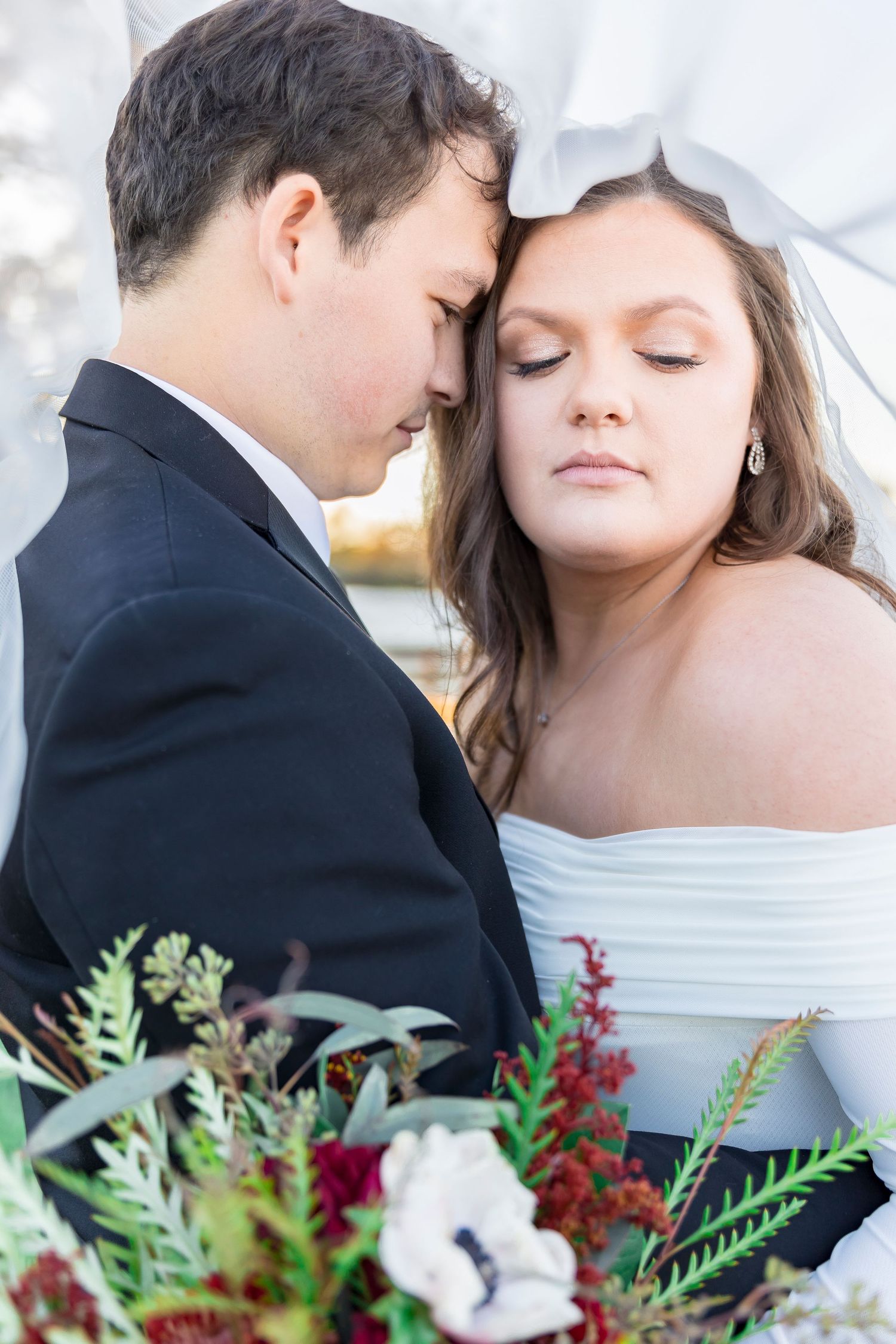 Intimate wedding portrait with dramatic florals and off-shoulder gown.