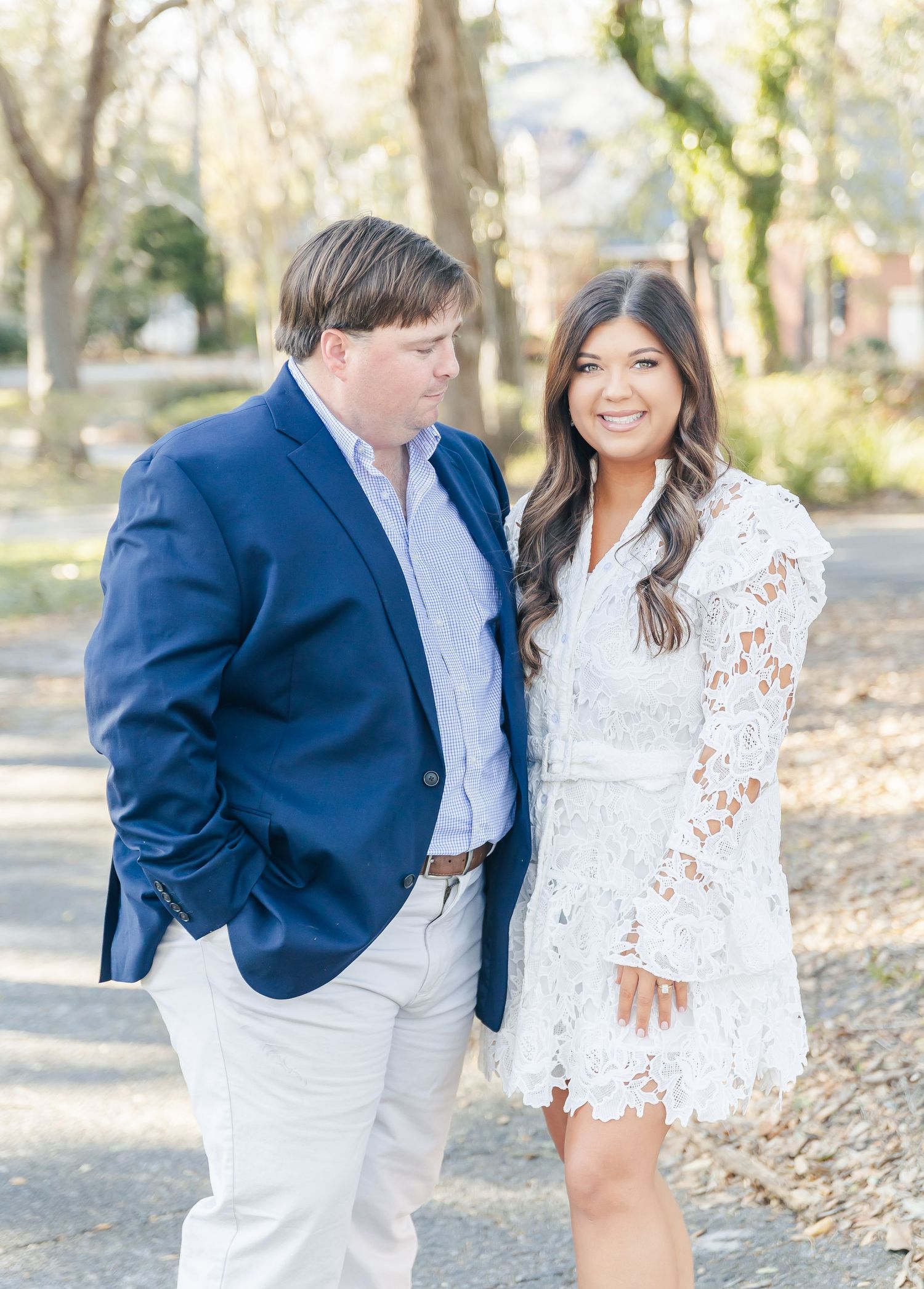 A couple stands together on a garden path, wearing coordinated navy and white outfits.