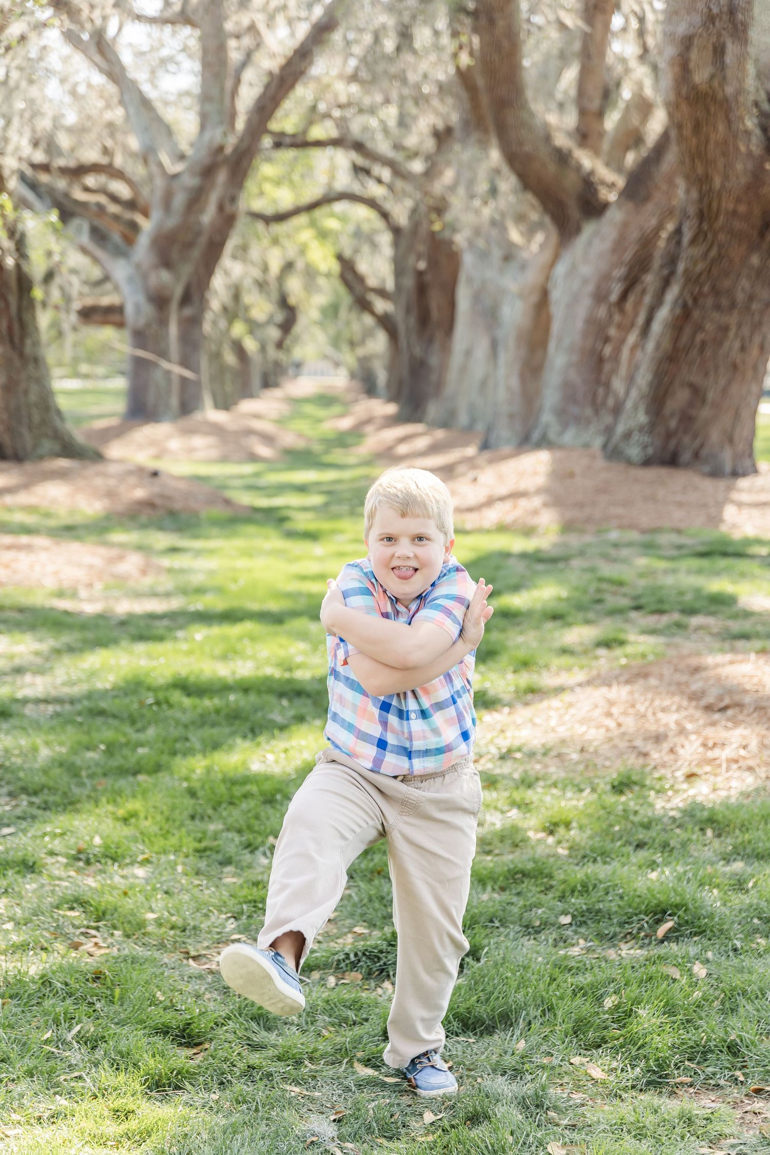 Dynamic dancing movement captured on grass beneath tree-lined pathway.