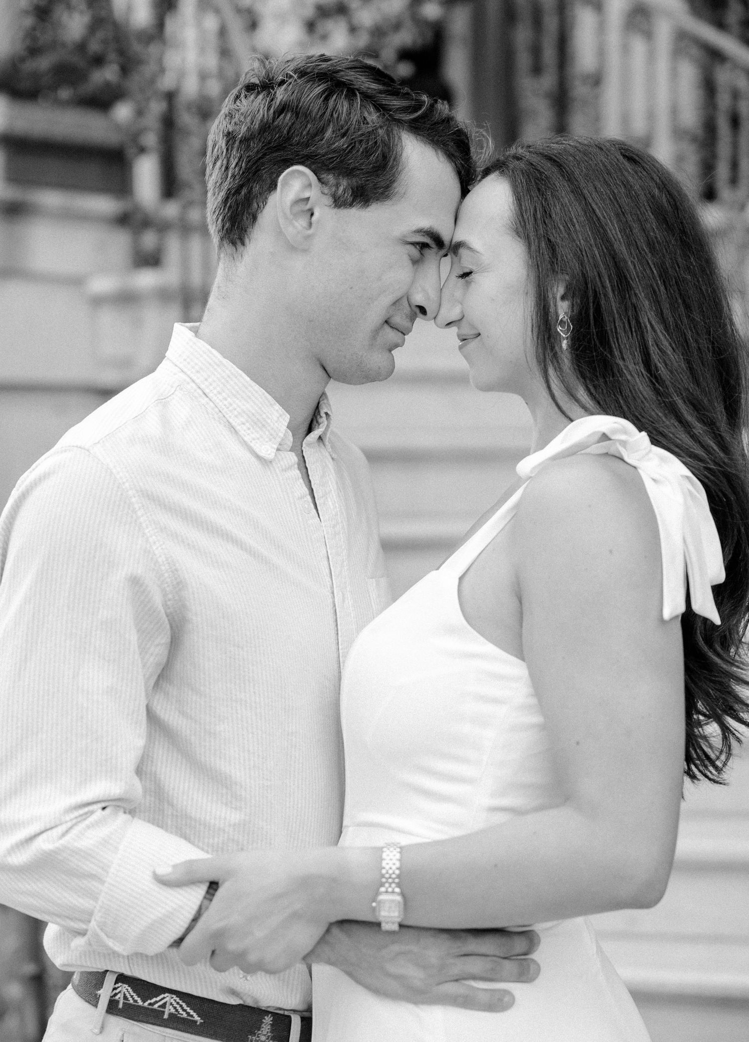 Black and white portrait of an engaged couple embracing and gazing into each other eyes outdoors.