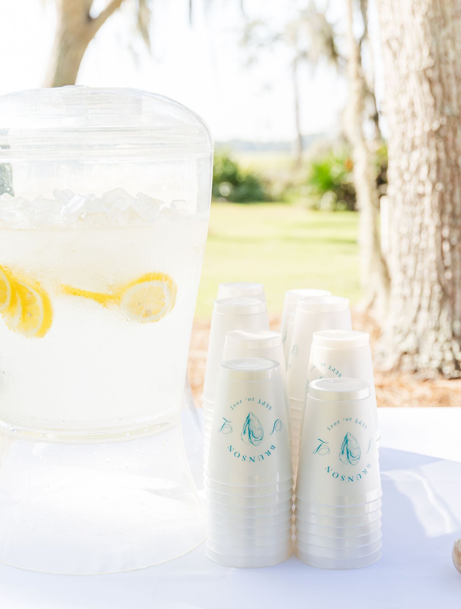 Refreshment station with lemon water dispenser and branded cups at an outdoor event.