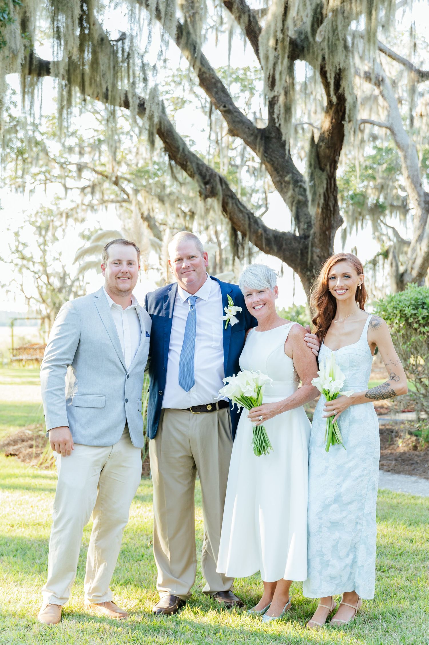 Wedding party poses together under Spanish moss draped trees in casual summer attire.